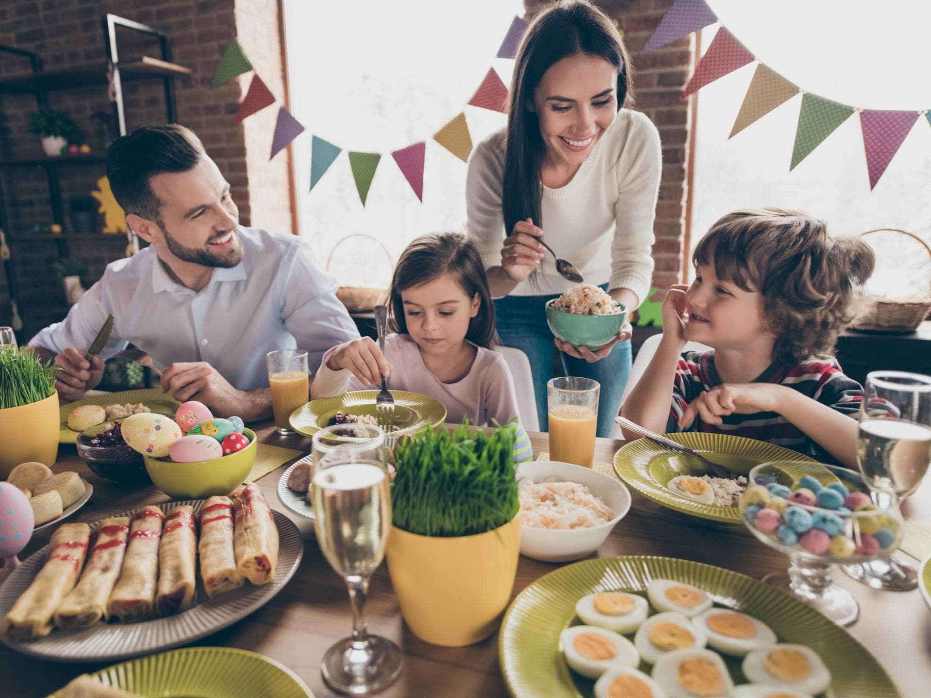 Vater und Mutter genießen ihr Osterfrühstück mit ihrer Tochter und ihrem Sohn.