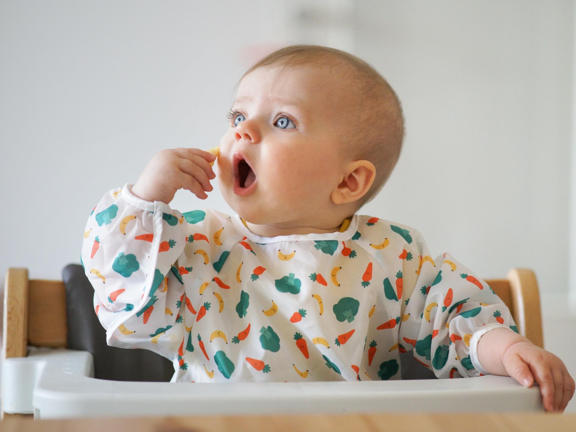 Baby steckt sich etwas zu Essen in den Mund. 