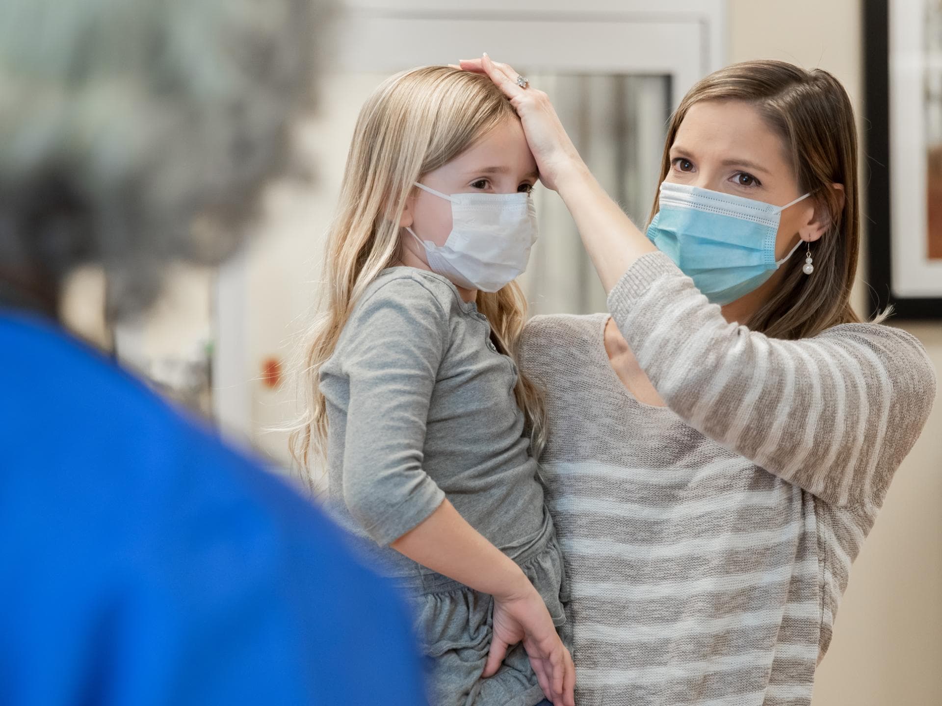 Den Kinderarzt zu wechseln, ist oft leider gar nicht so leicht. Mutter mit ihrer kranken Tochter am Empfang einer Kinderarztpraxis