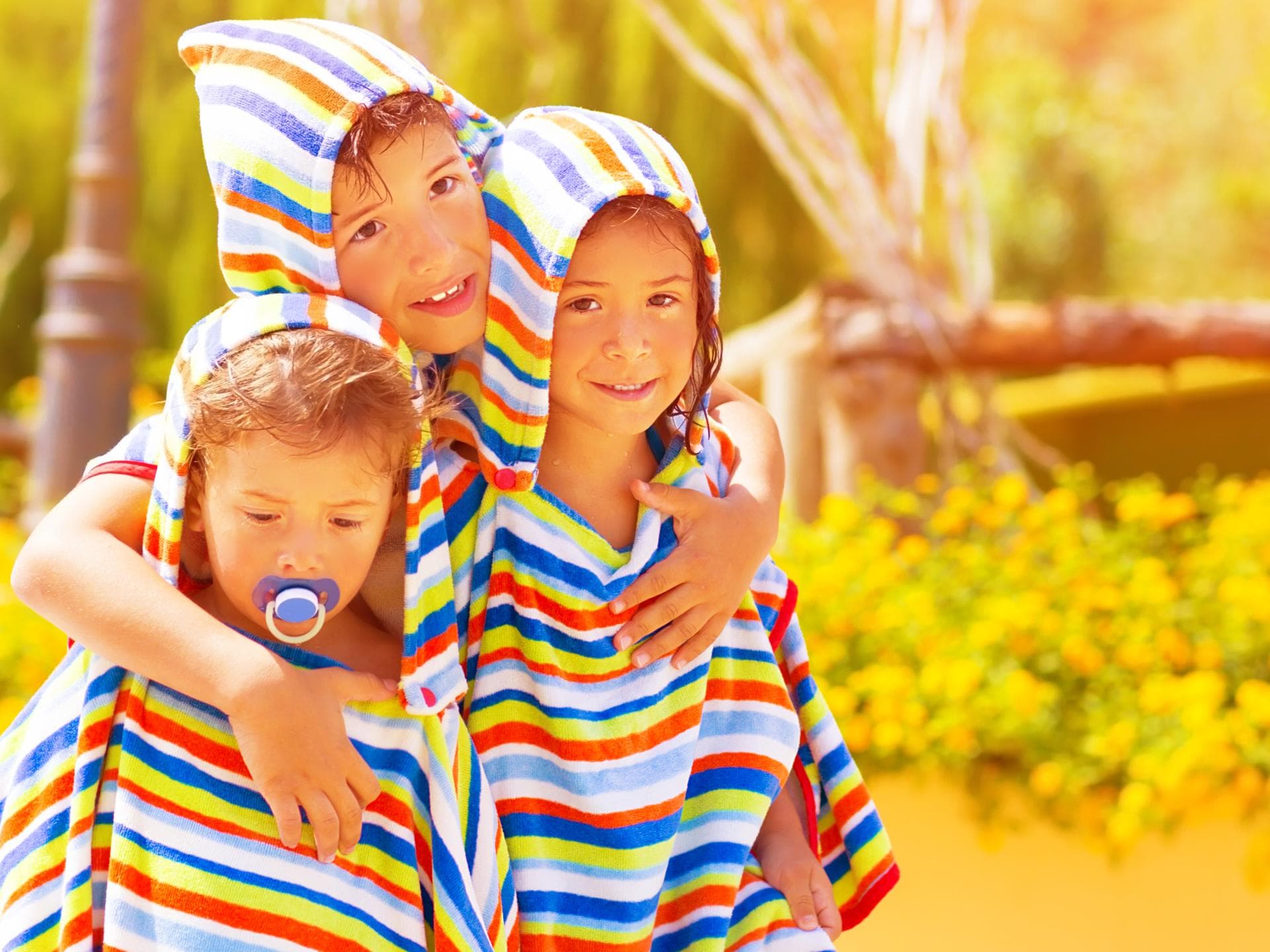 Drei Kinder mit Strandponcho