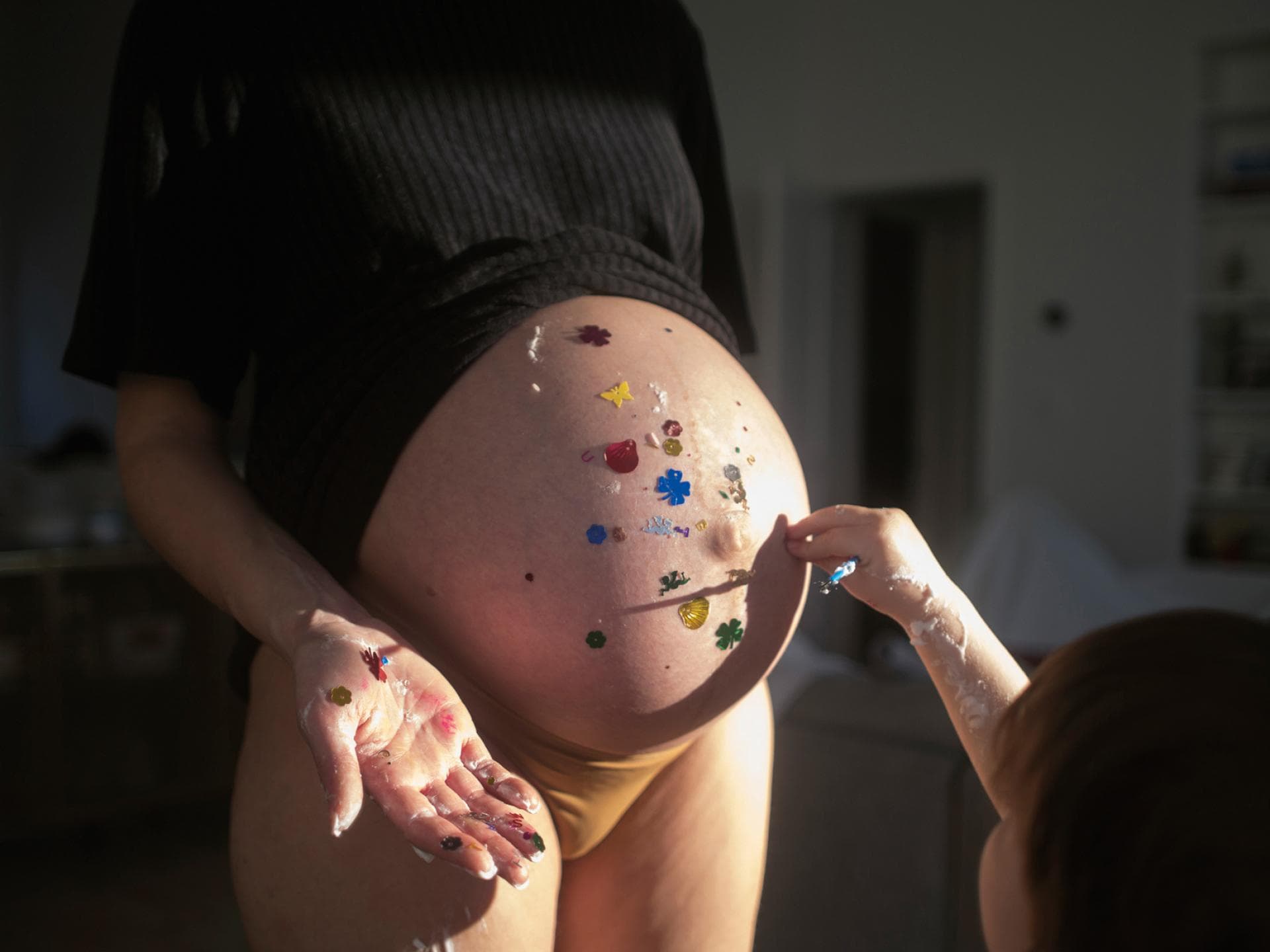 Ein Babybauch, der hübsch dekoriert wird von einem Kind
