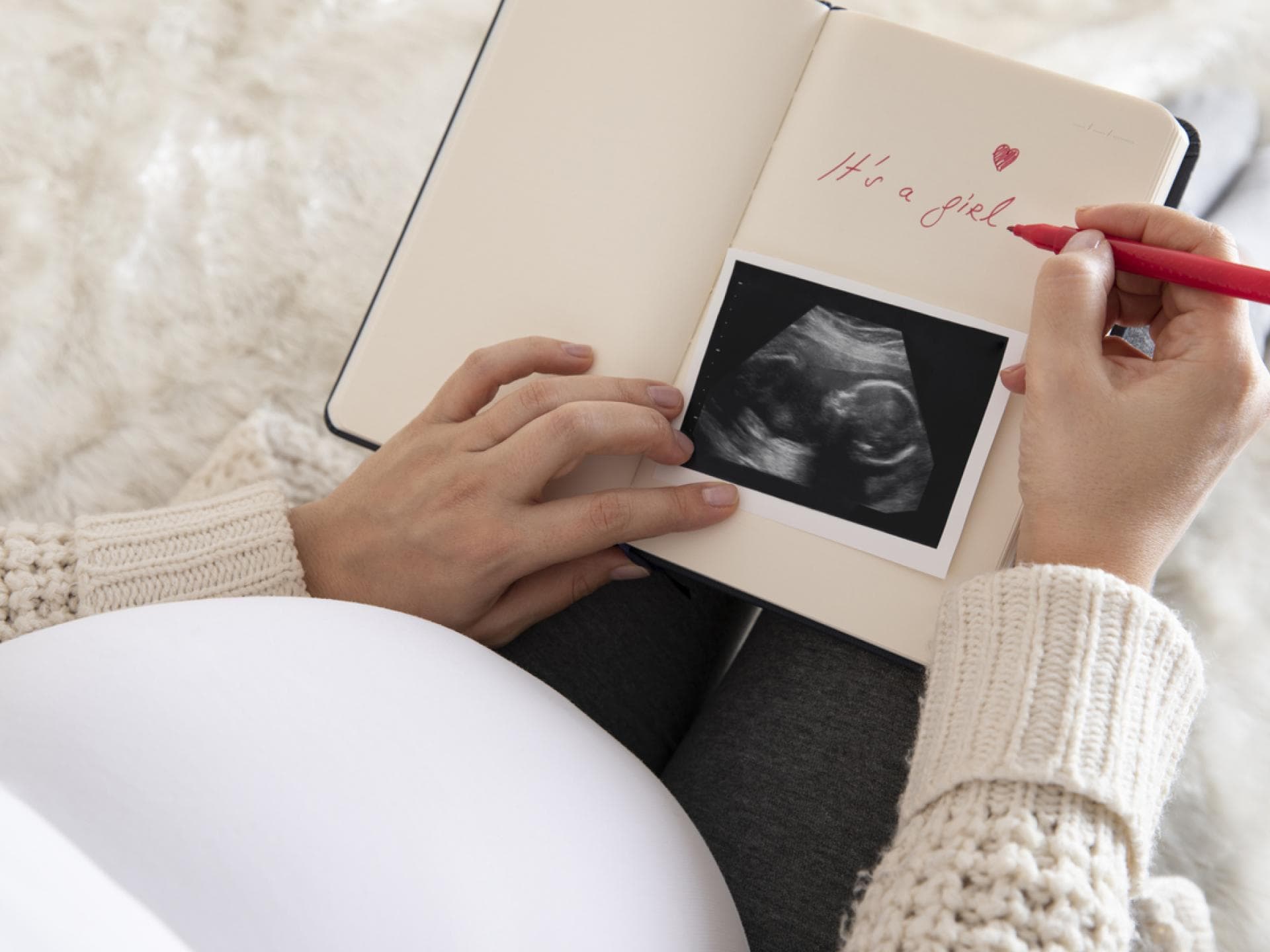 Eine schwangere Frau schreibt in ihr Baby-Tagebuch und zeigt ihr Ultraschallbild. Eine schwangere Frau schreibt in ihr Baby-Tagebuch und zeigt ihr Ultraschallbild.