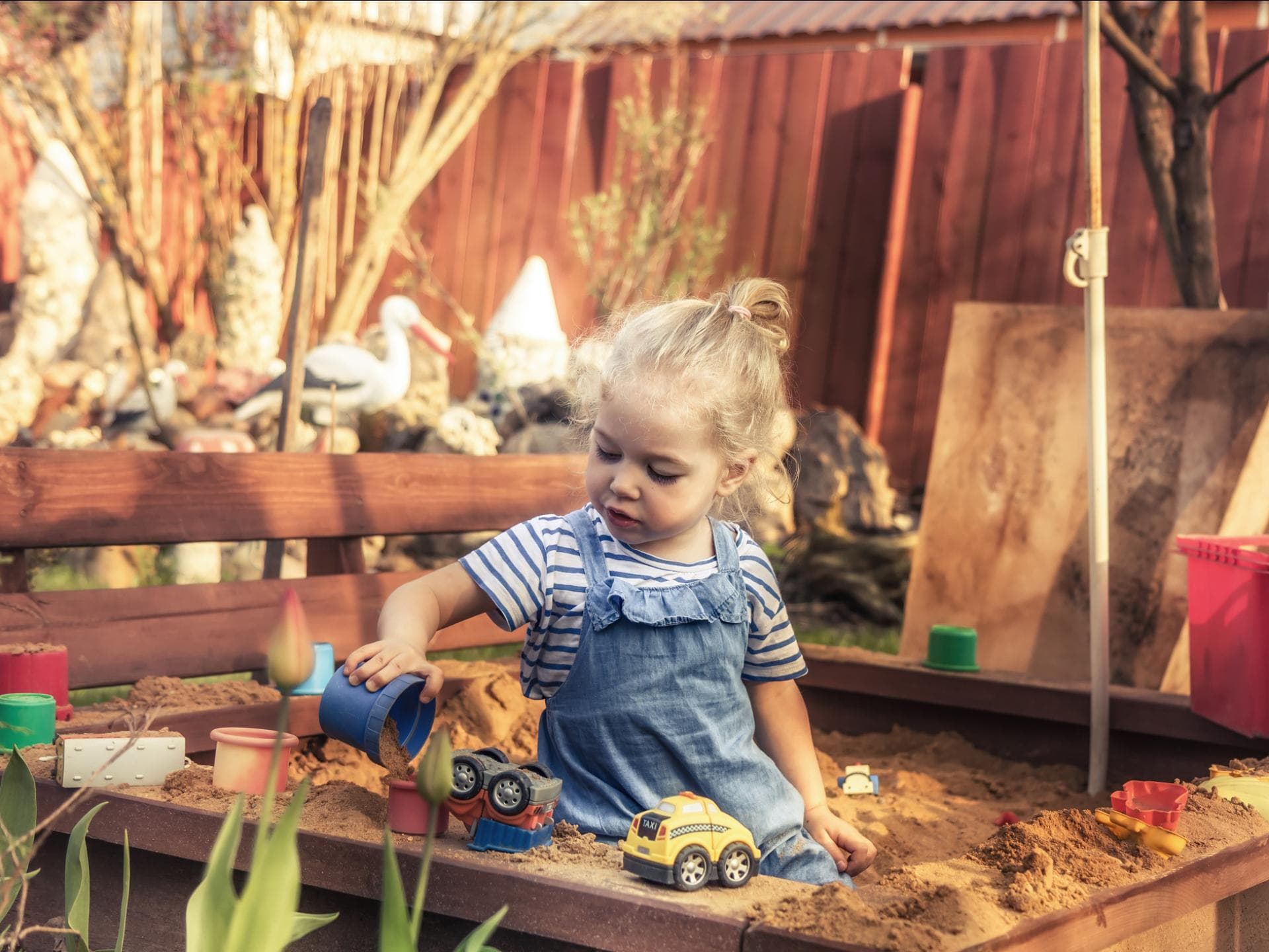 Sandkiste ist out? Gartenspielzeug, das eure Kinder begeistern wird Kleines Mädchen spielt mit Autos in der Sandkiste