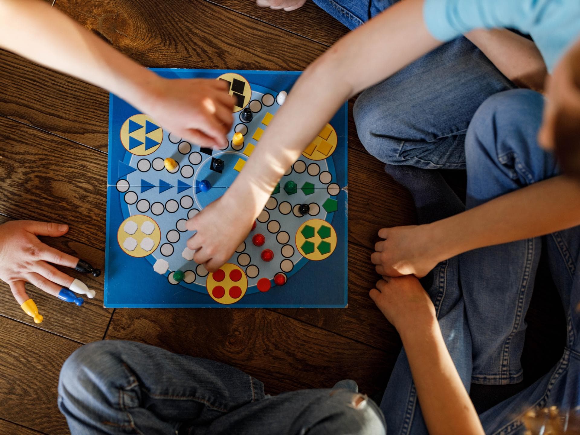 Gesellschaftsspiele für Kinder können der ganzen Familie Spaß machen. Viele Kinder sitzen um ein Gesellschaftsspiel herum.
