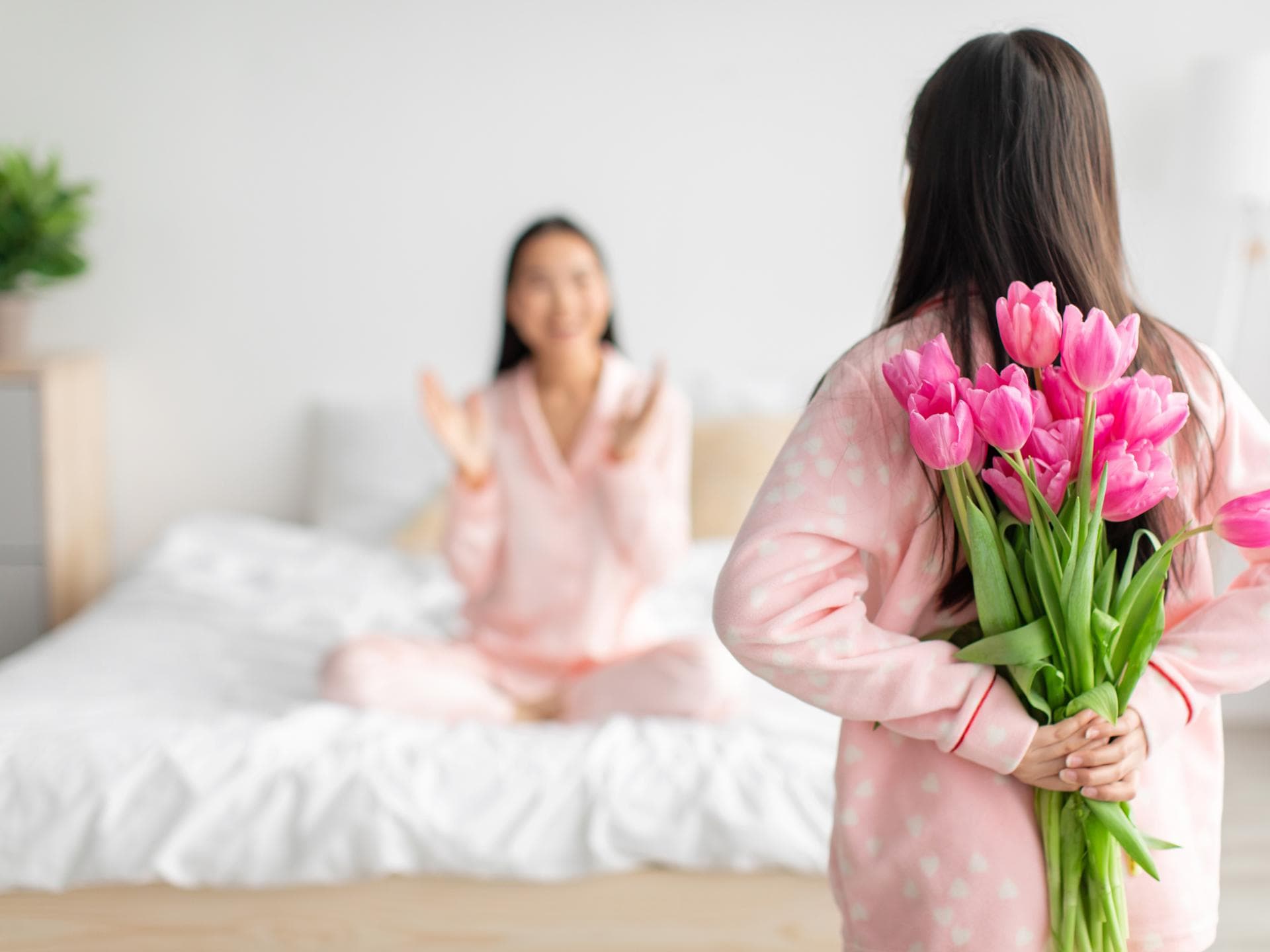 Mädchen versteckt Blumen für ihre Mutter hinter ihrem Rücken