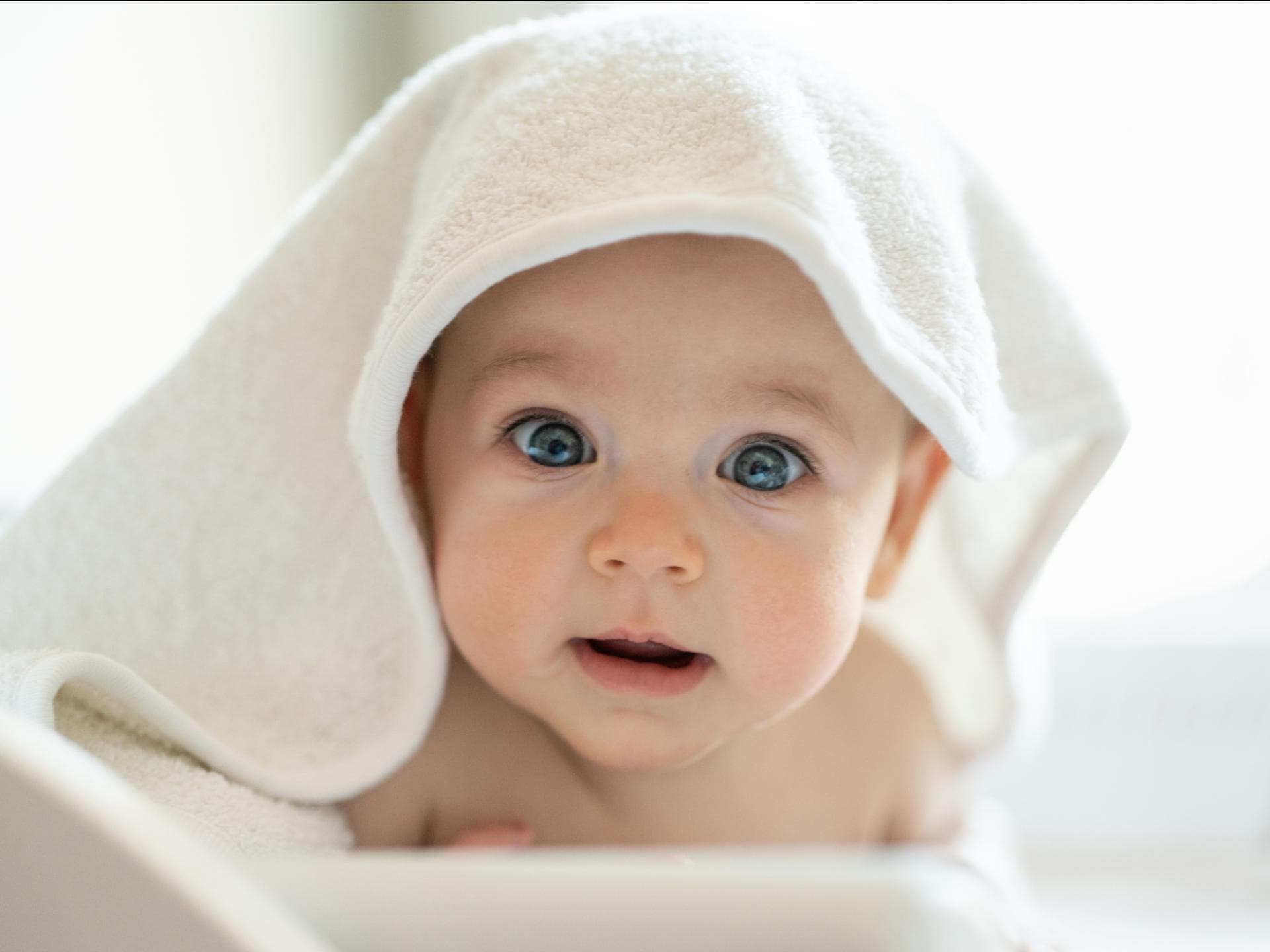 Ein Baby versteckt sich unter einem Handtuch.