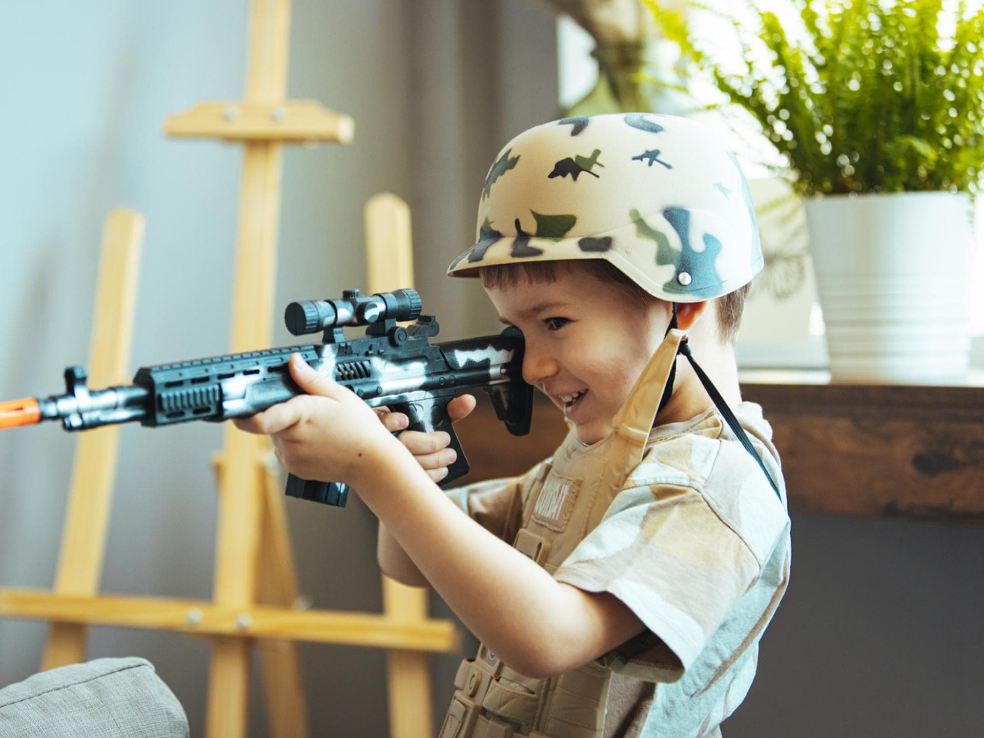 Kleiner Junge mit Tarn-Helm und Spielzeugwaffe Kleiner Junge mit Tarn-Helm und Spielzeugwaffe