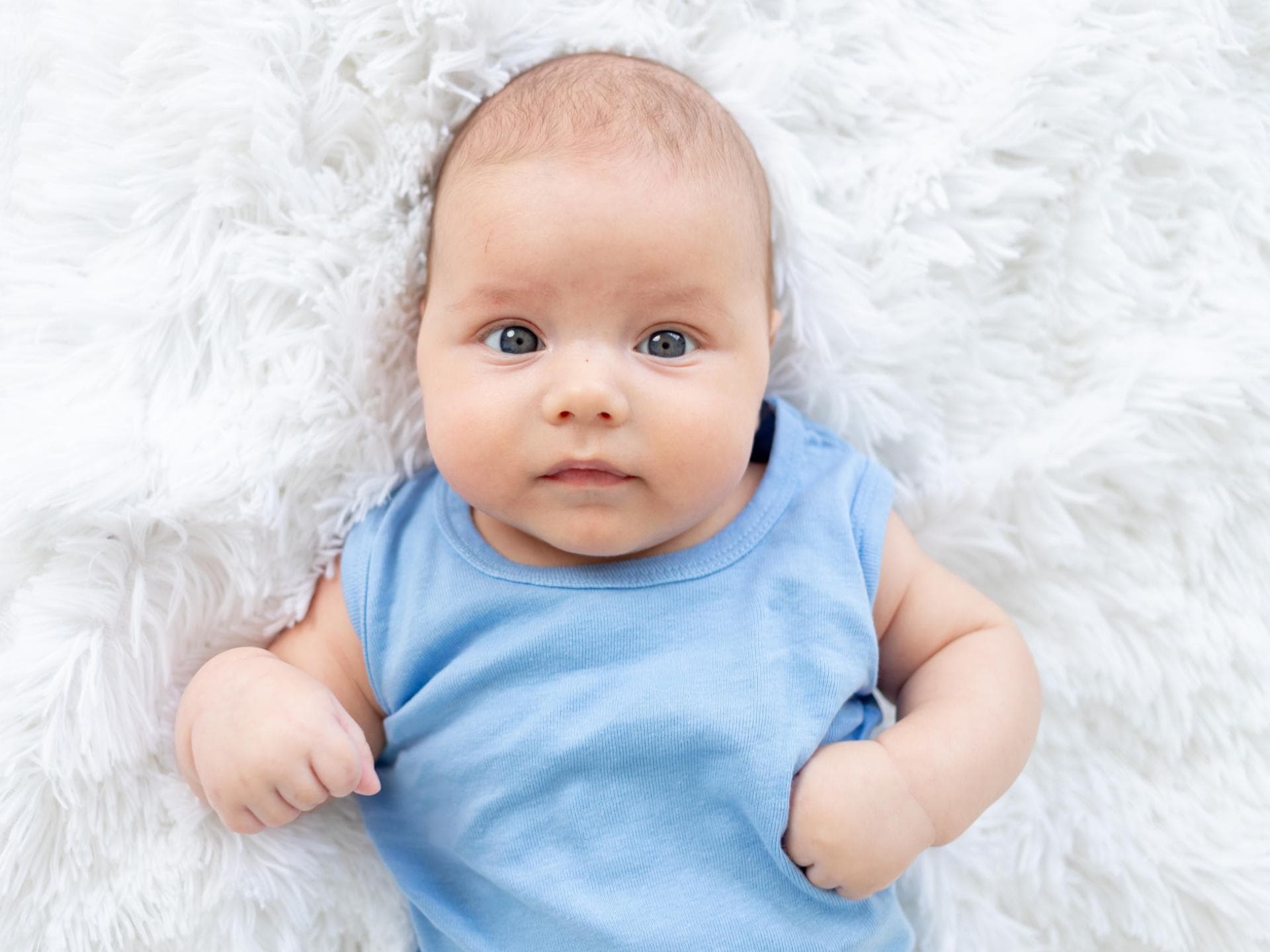 Vorsicht bei der Namenswahl! Baby in blauem Body auf einem Fell