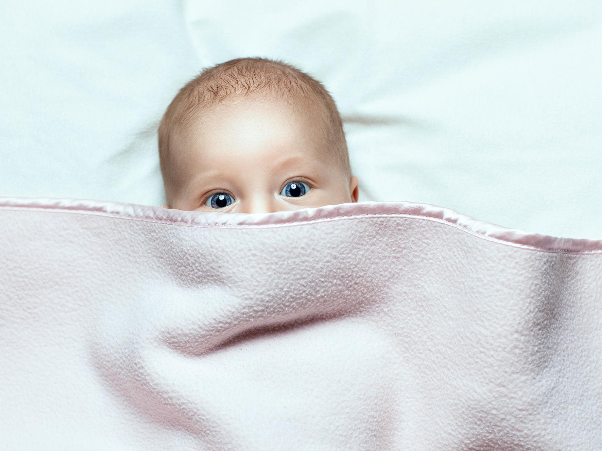 Baby versteckt sich unter einer Decke.