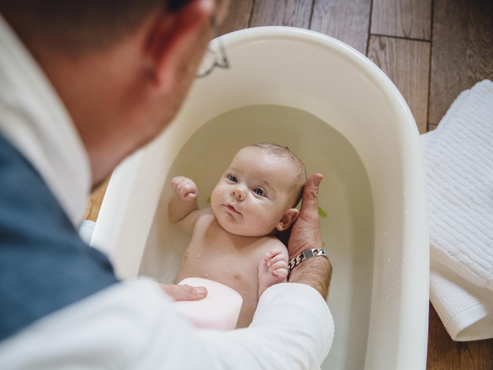 Wie oft sollte man Babys baden? Diese Richtlinie kann helfen. Ein Vater badet sein Baby in deiner Babybadewanne