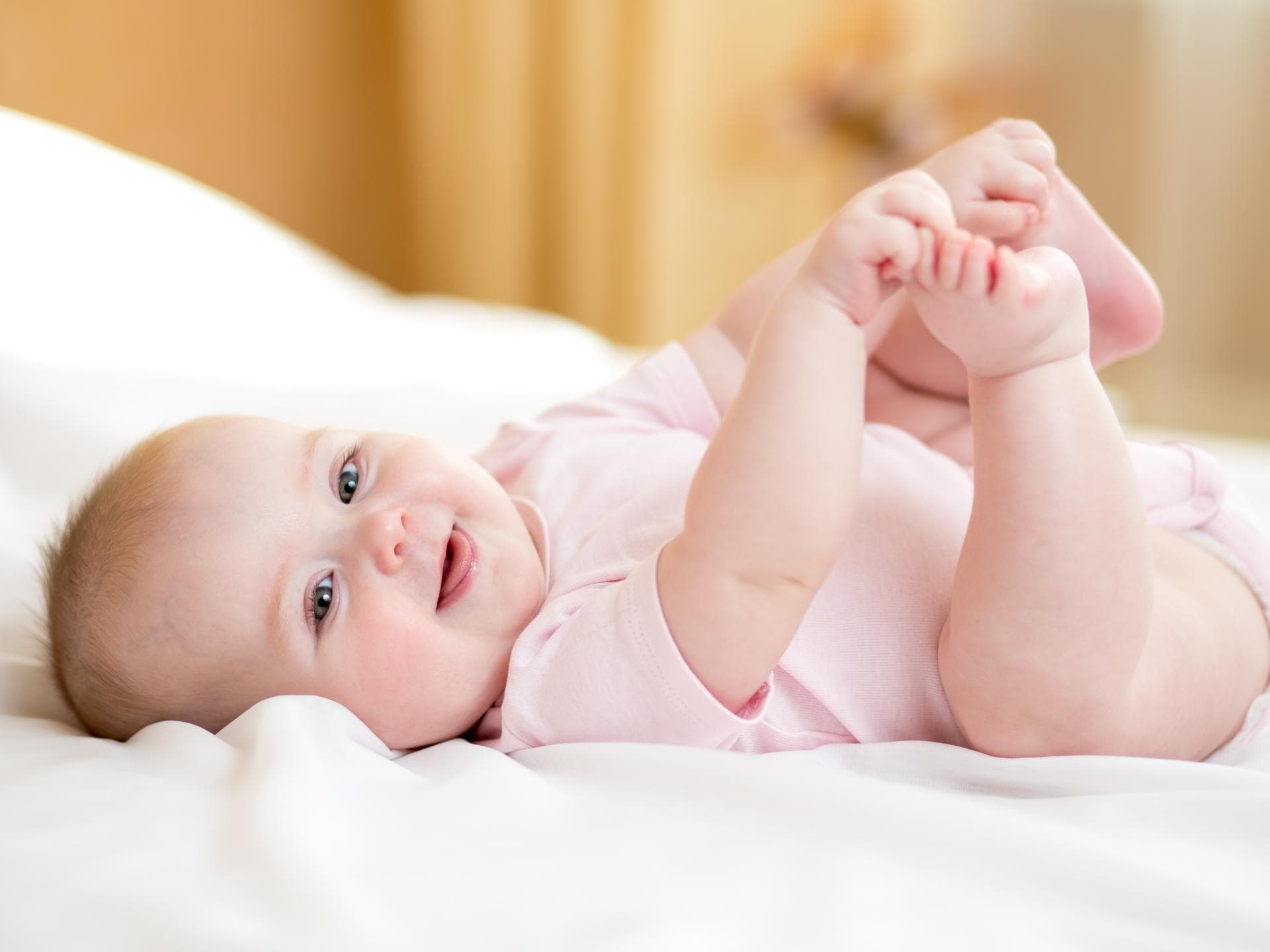 In unserer Übersicht findet ihr schöne Vorschläge für Mädchennamen mit R. Ein kleines Baby liegt auf dem Rücken und hält sich die Füße.