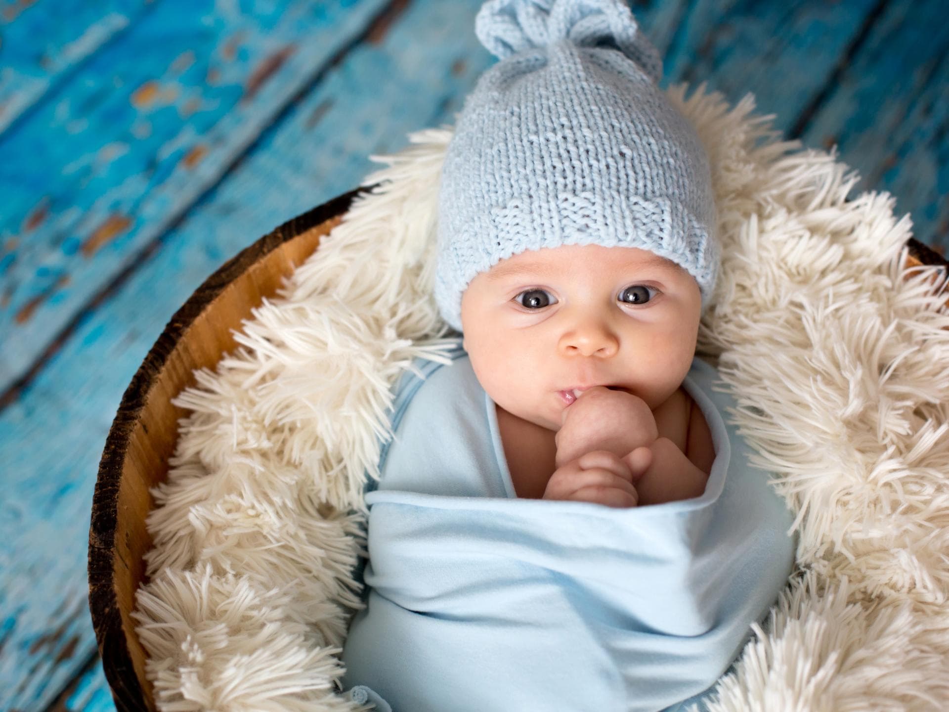 Von Aaron bis Aurelius: Wir zeigen euch schöne Jungennamen mit A. Ein kleines Baby liegt in einem kuscheligen Bett.