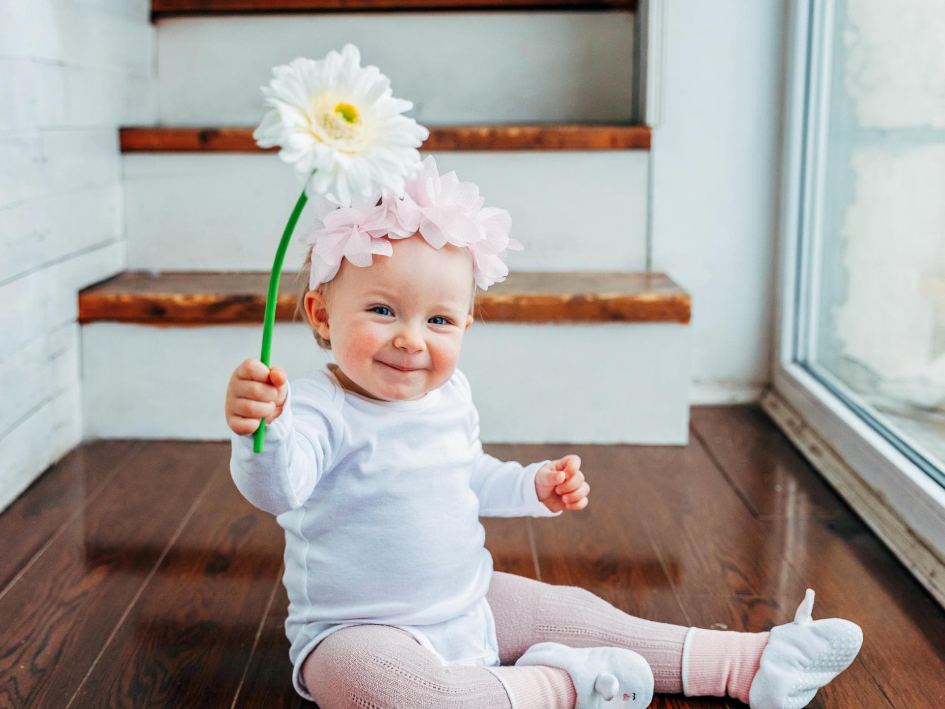 Ein kleines Mädchen lacht und hält eine Blume in der Hand. 