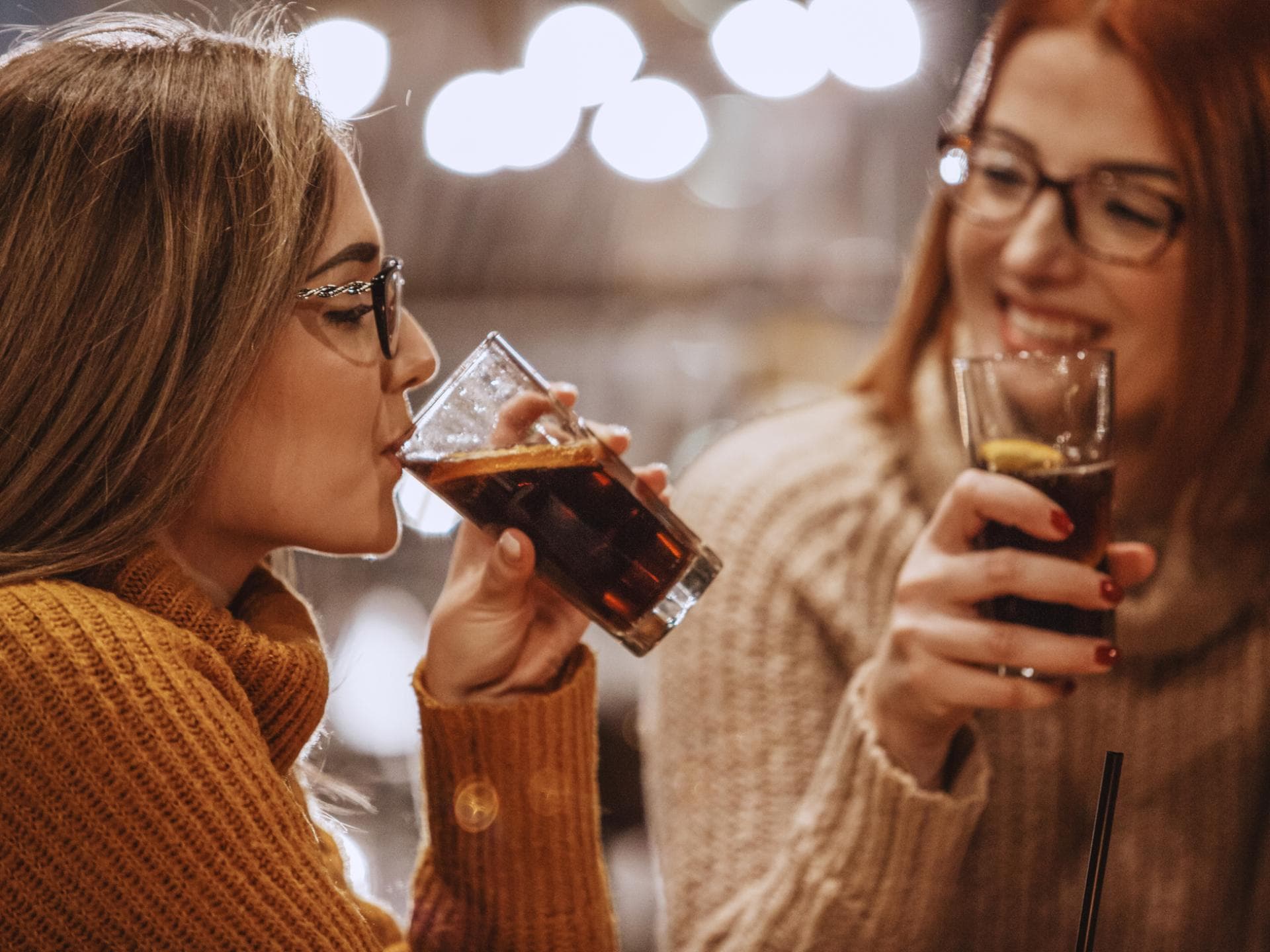 Wie viel Cola ist in der Schwangerschaft noch unbedenklich? Zwei Frauen trinken Coca Cola.