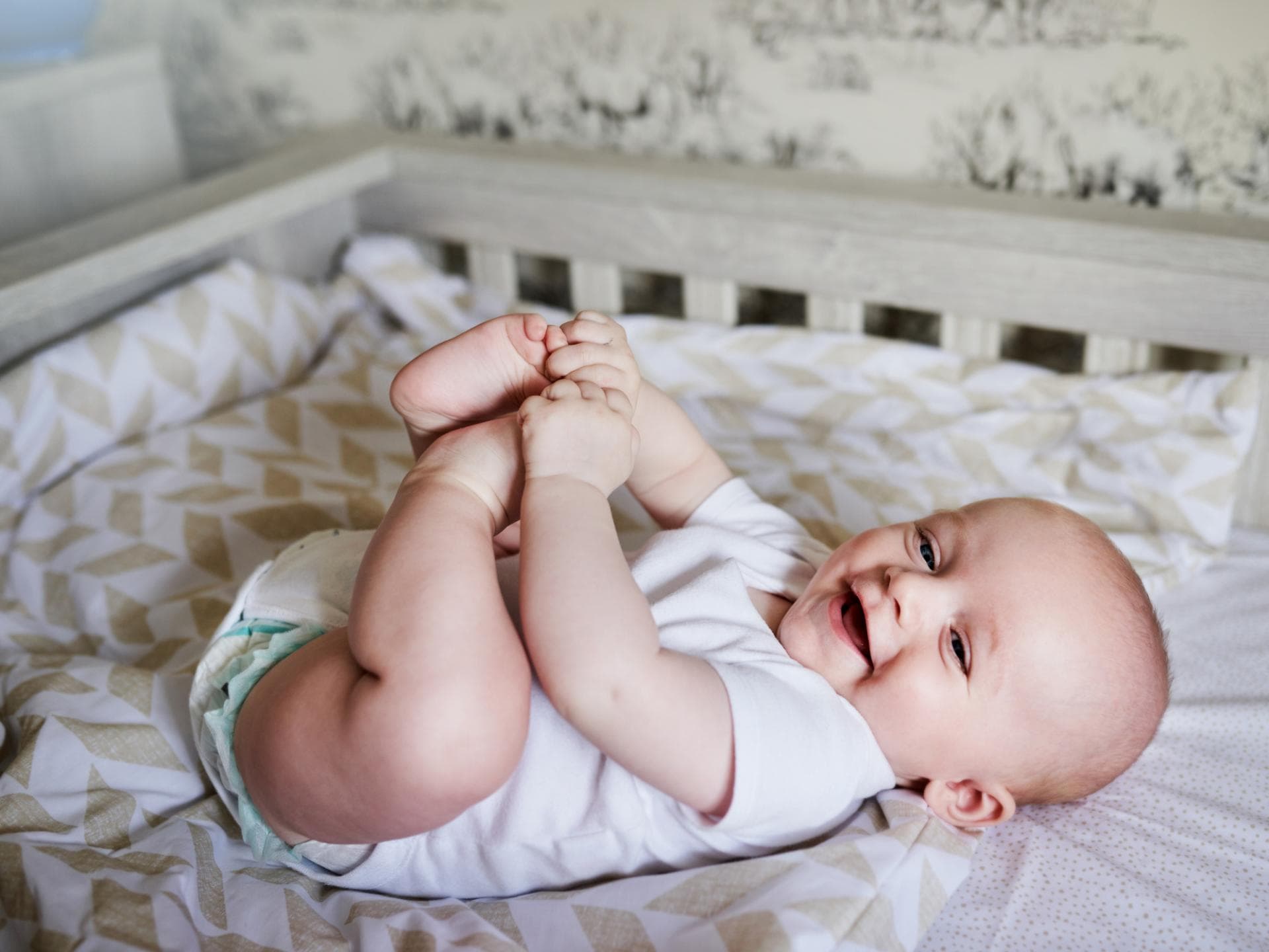 In diesem Artikel dreht sich alles um Mädchennamen mit X. Ein Baby liegt in seinem Bett und hält sich die Füße.