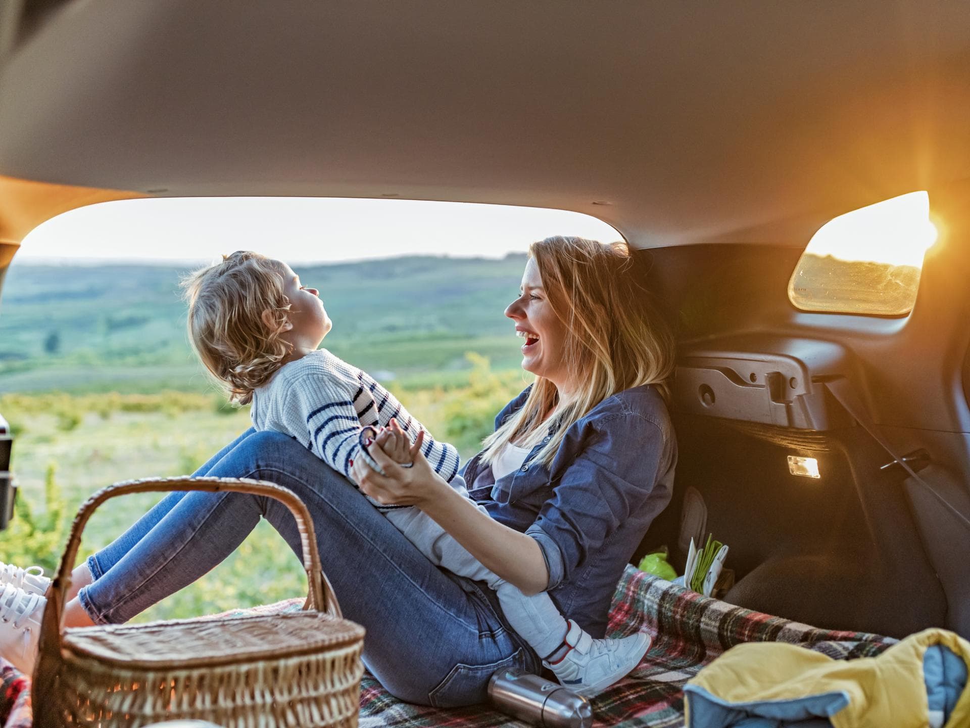 Mutter und Kind sitzen im Van und haben ein Picknick dabei.
