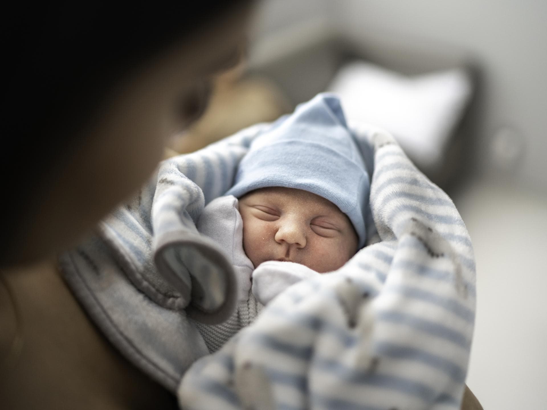 Hier findet ihr eine breite Auswahl an Jungennamen mit S. Ein kleines Baby liegt in den Armen seiner Mutter.