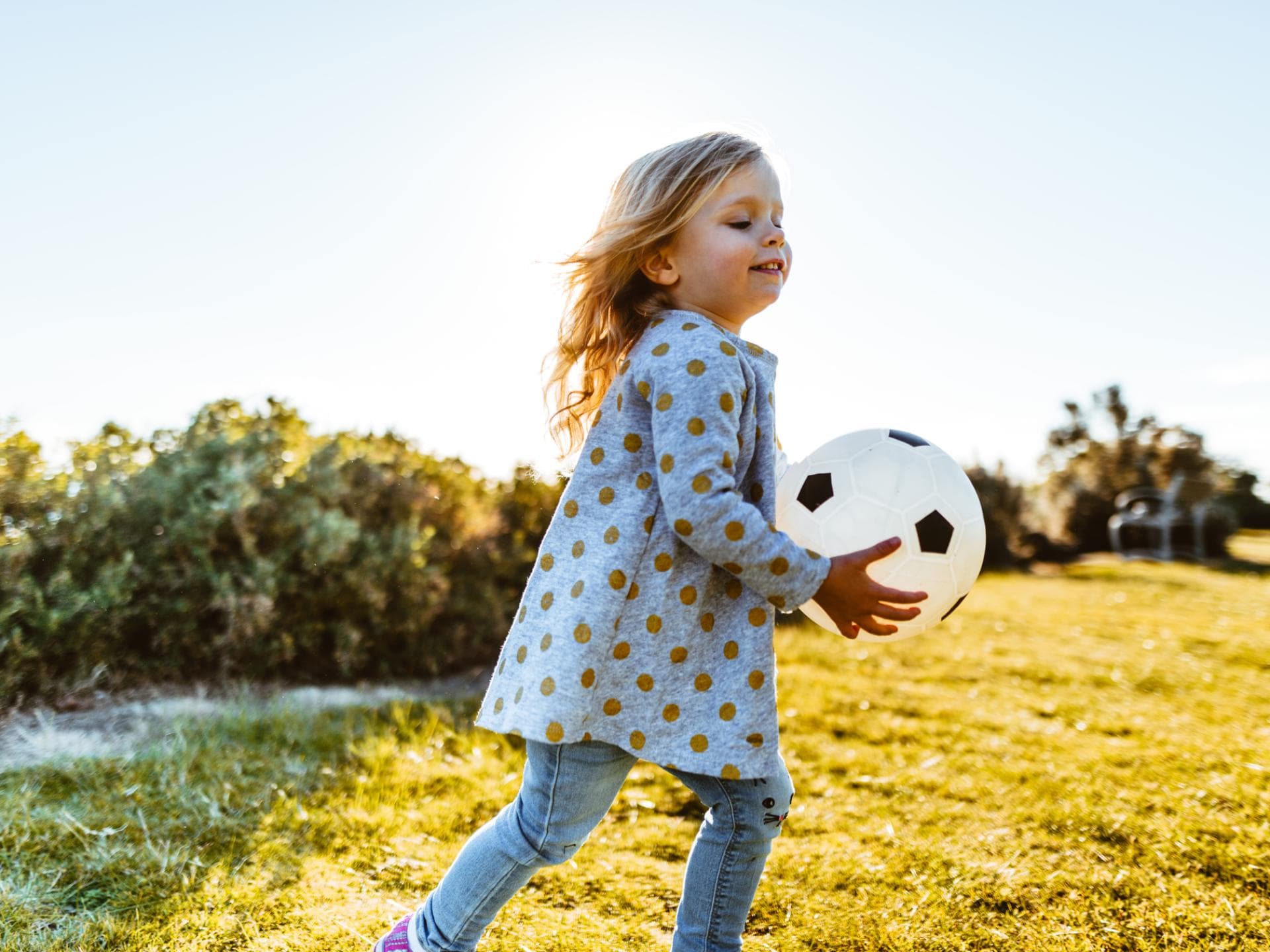 Coole Ballspiele für Kinder Ein Mädchen spielt mit einem Ball.
