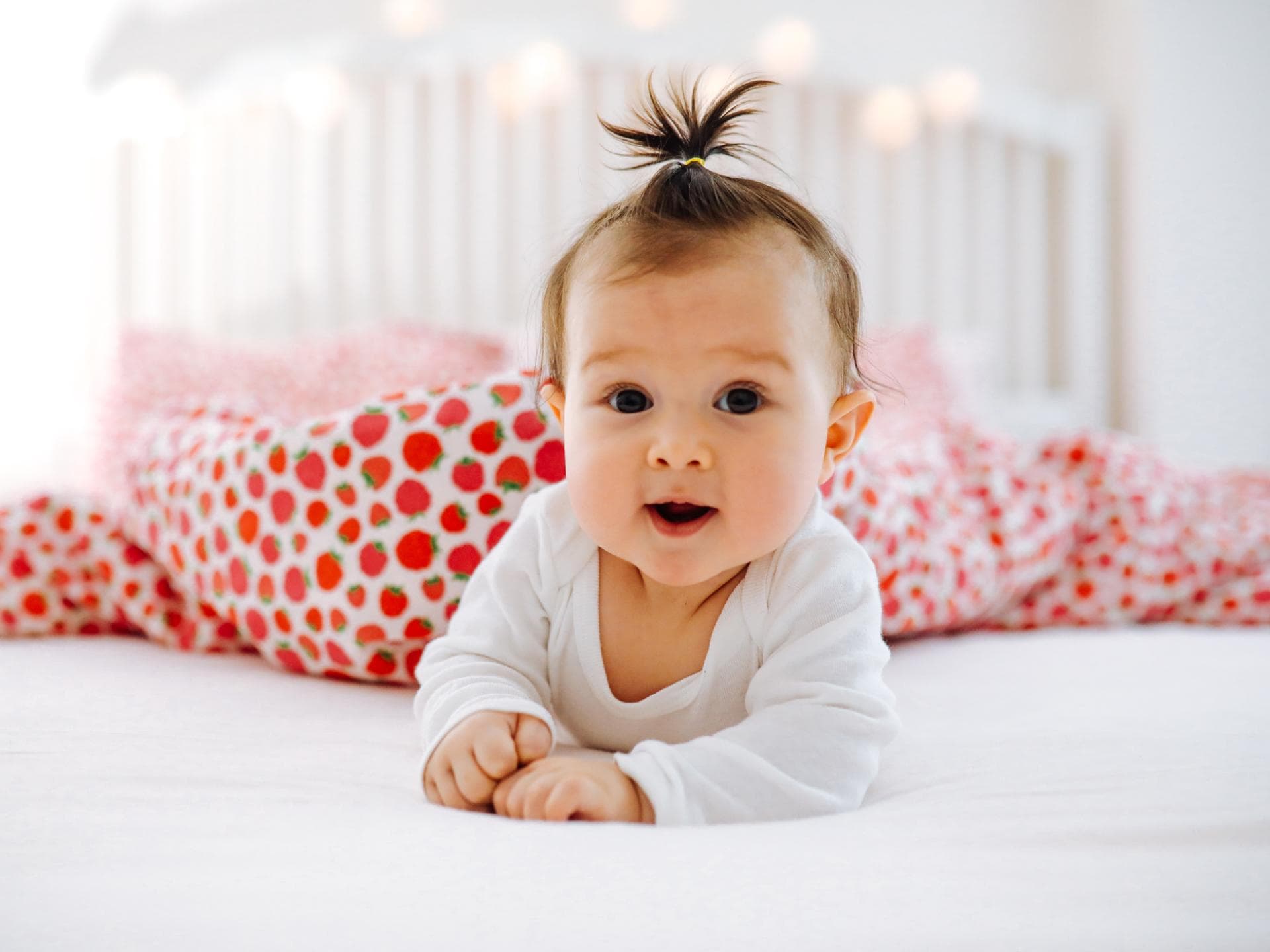 Ein Baby liegt lächelnd auf dem Bett.