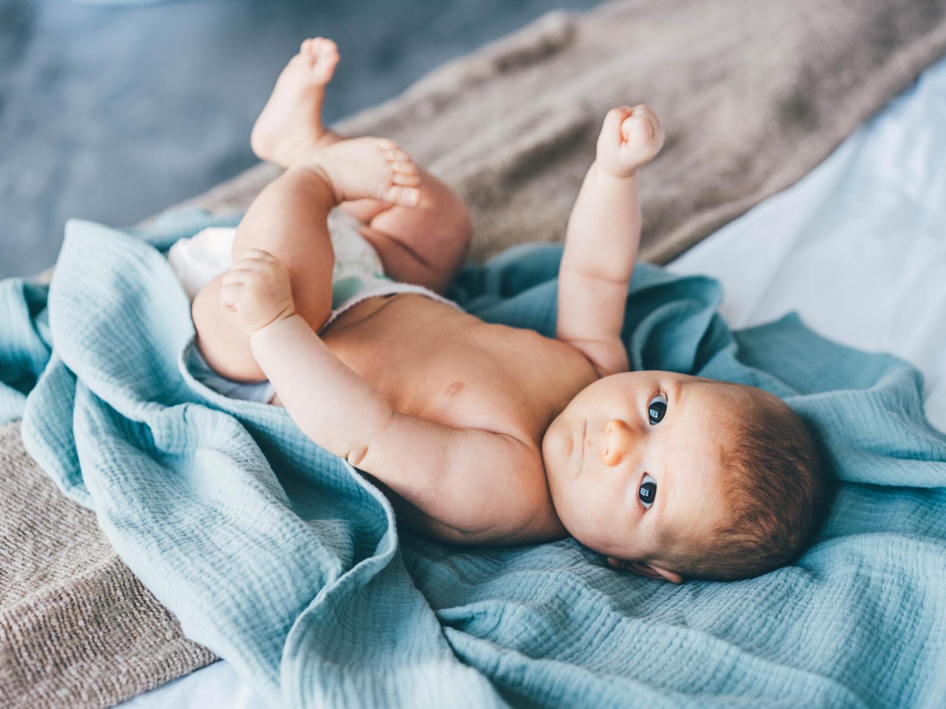 Ein Baby liegt auf einem blauen Tuch.