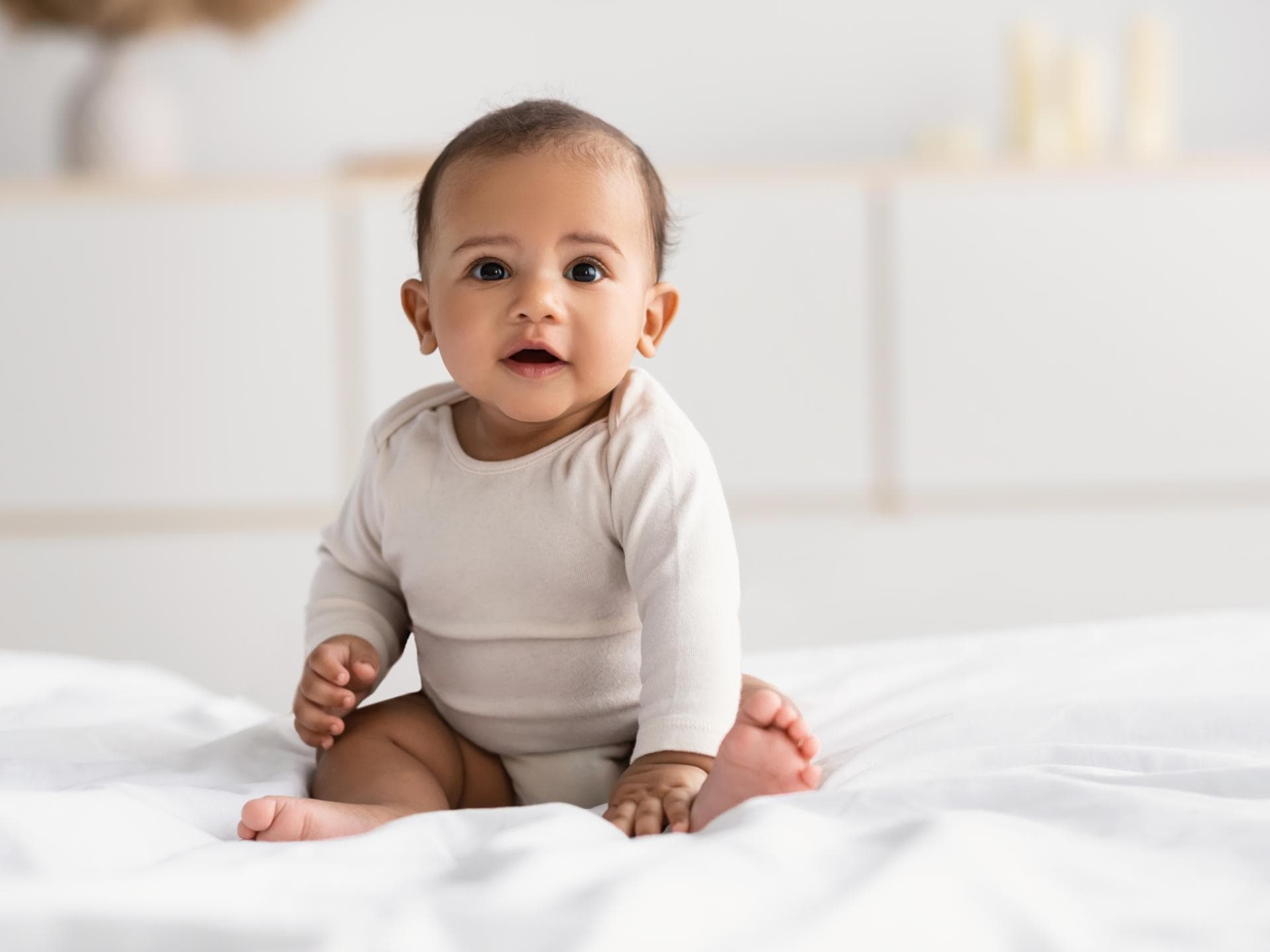 Ein kleiner Junge sitzt fröhlich auf dem Bett.