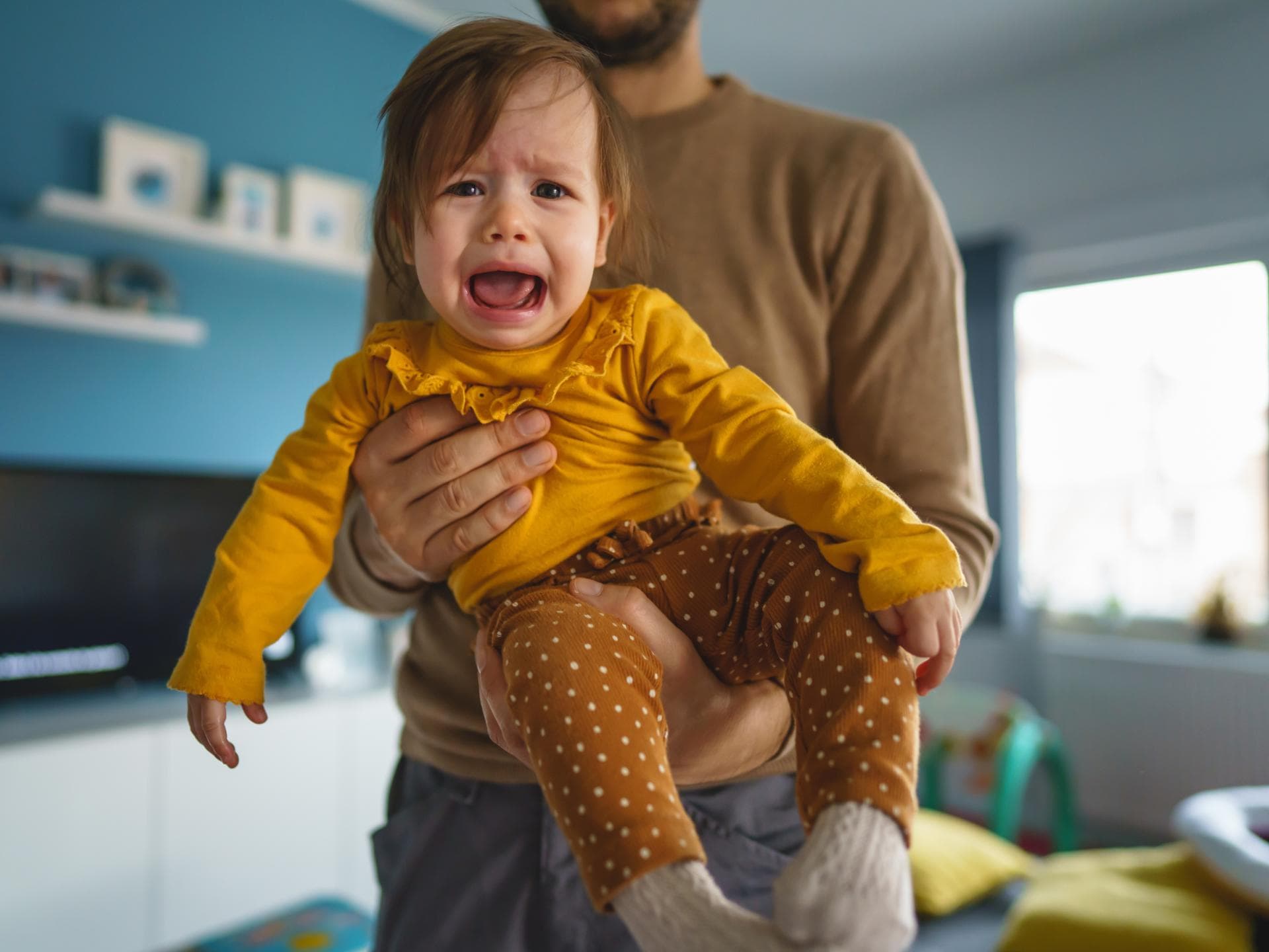 Kind schreit auf Papas Arm. Kind schreit auf Papas Arm.