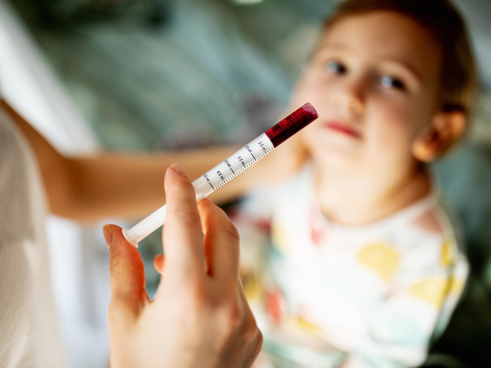 Mutter gibt ihrem Sohn Fiebersaft mit einer Pipette Mutter gibt ihrem Sohn Fiebersaft mit einer Pipette