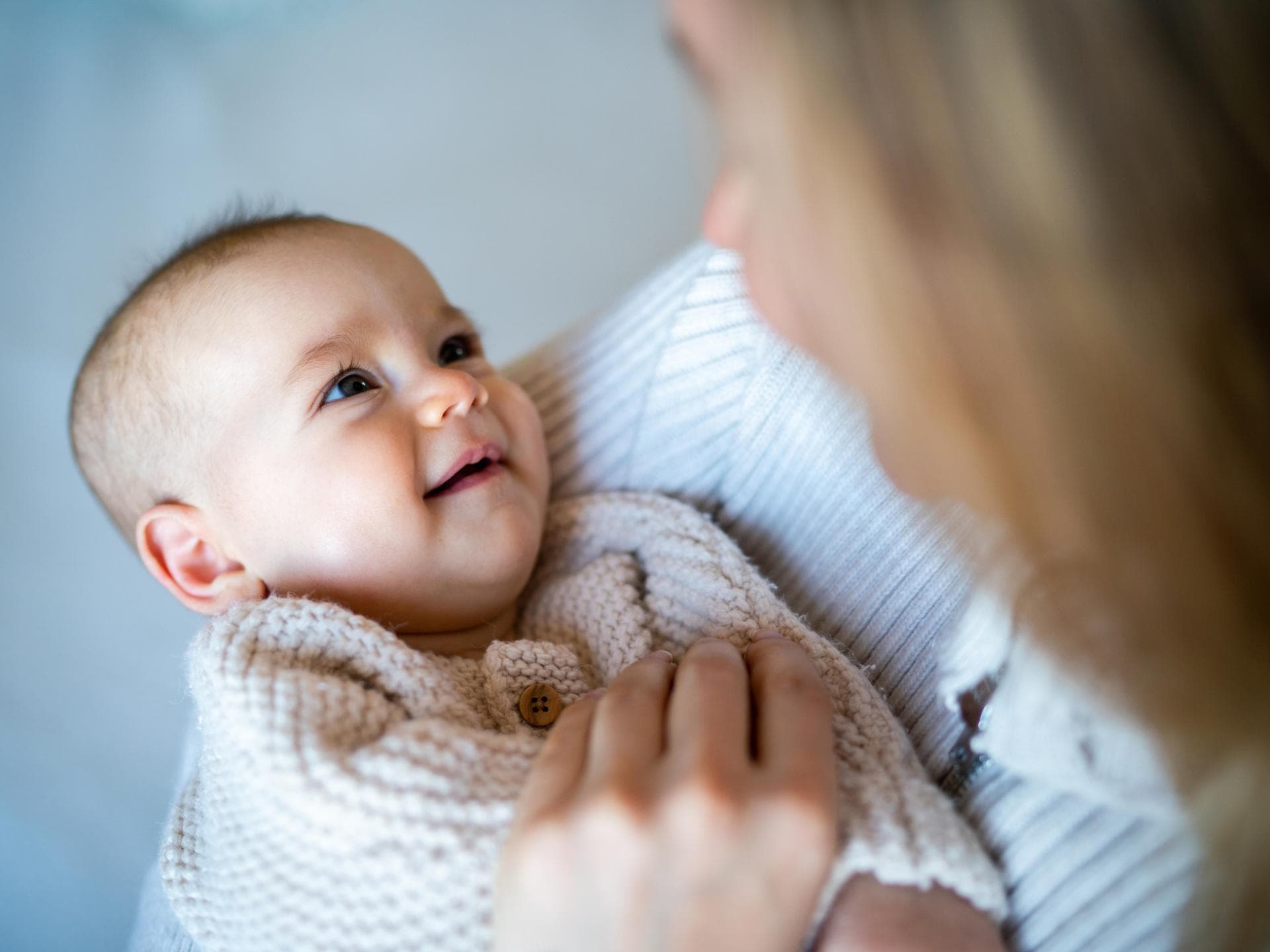 Von Xander bis Xhenis: Wir haben Jungennamen mit X für euch zusammengestellt. Eine Mutter hat ihr Baby auf dem Arm und es lächelt.