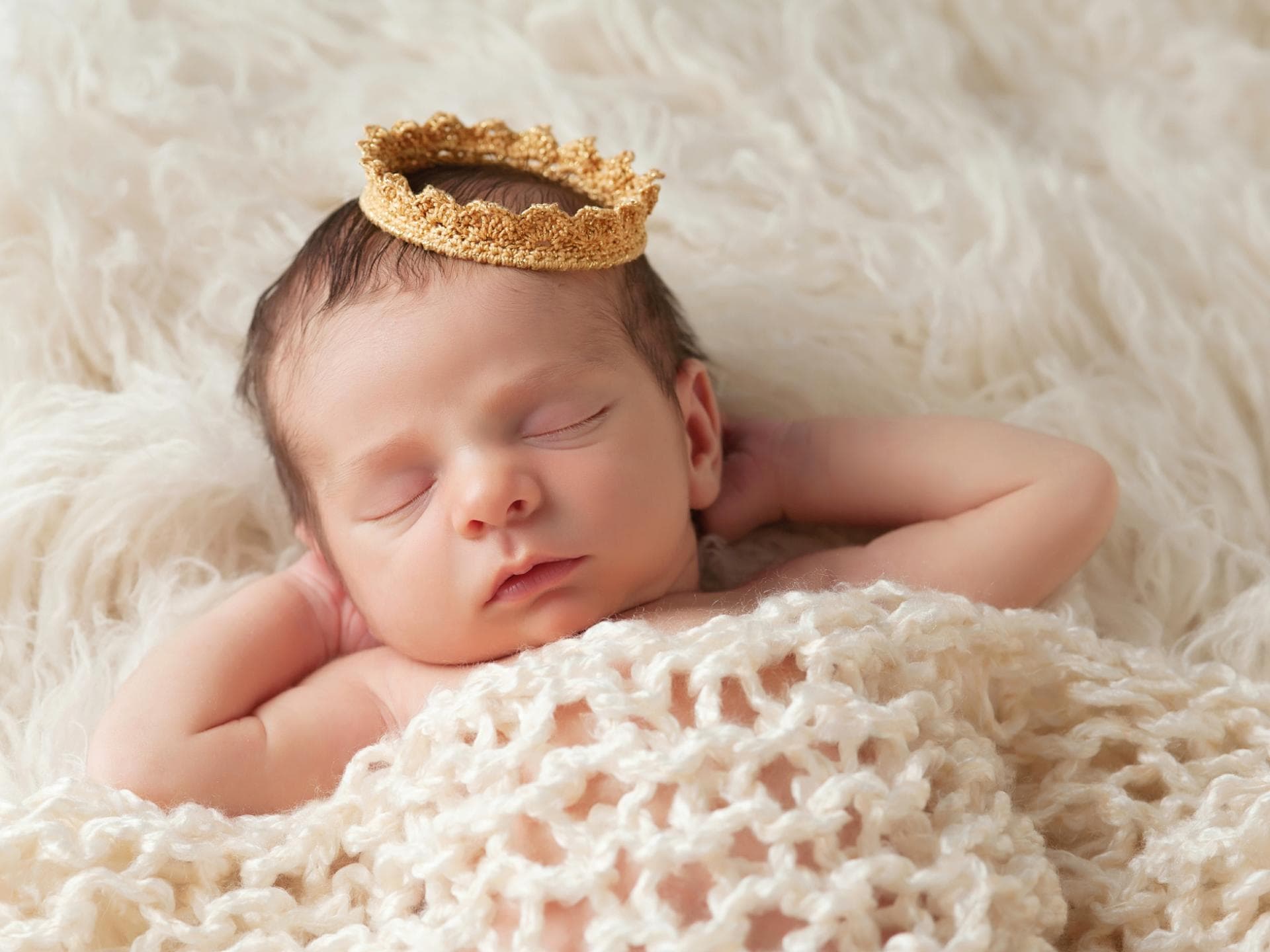 Königliche Namen sind nicht nur etwas für kleine Royals. Ein Baby schläft mit einer Krone auf dem Kopf.