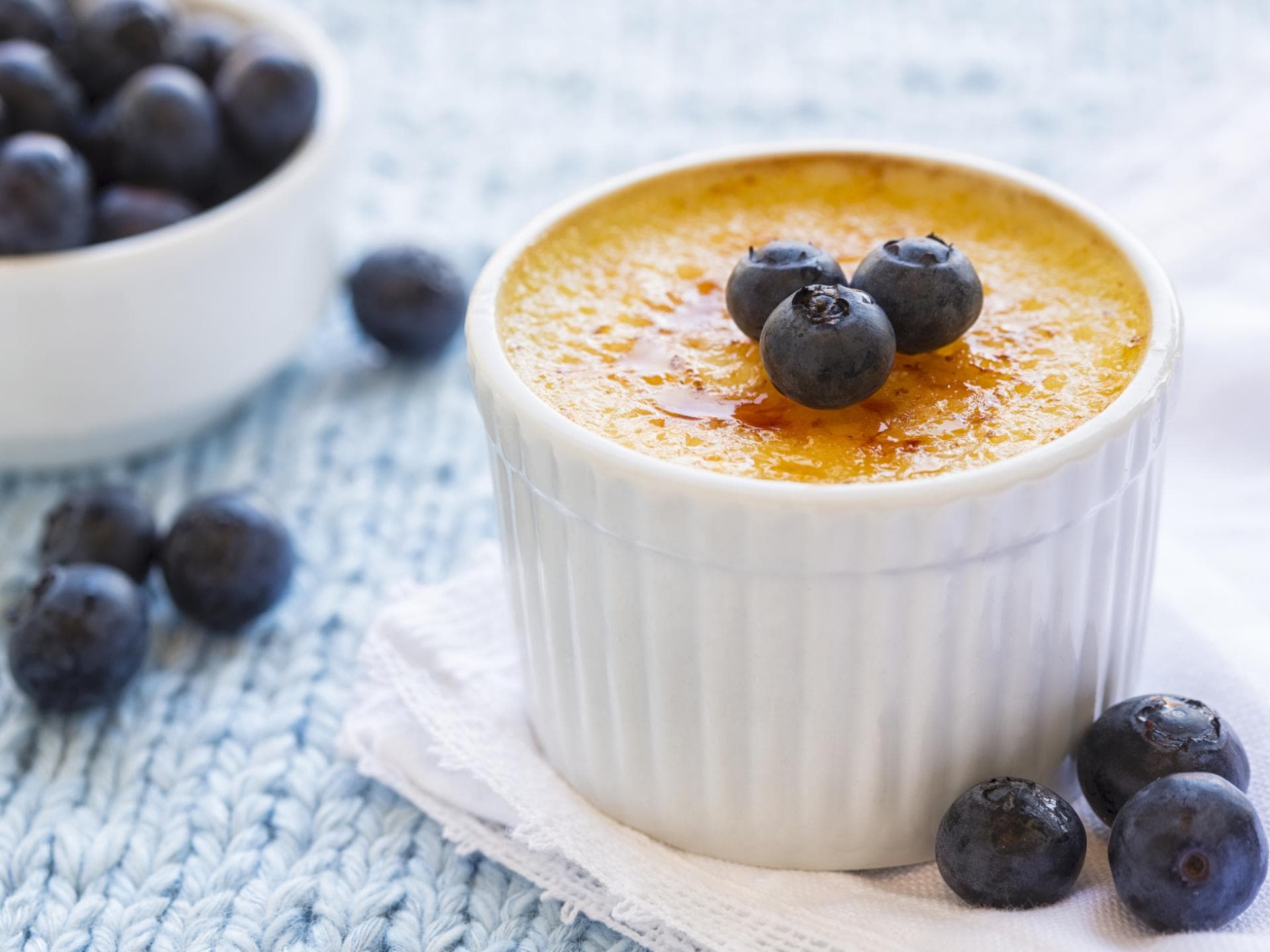 Für viele der Favorit zum Nachtisch. Aber ist Crème brulée auch für werdende Mamas unbedenklich? Eine Crème brulée steht auf dem Tisch und ist mit Blaubeeren garniert.