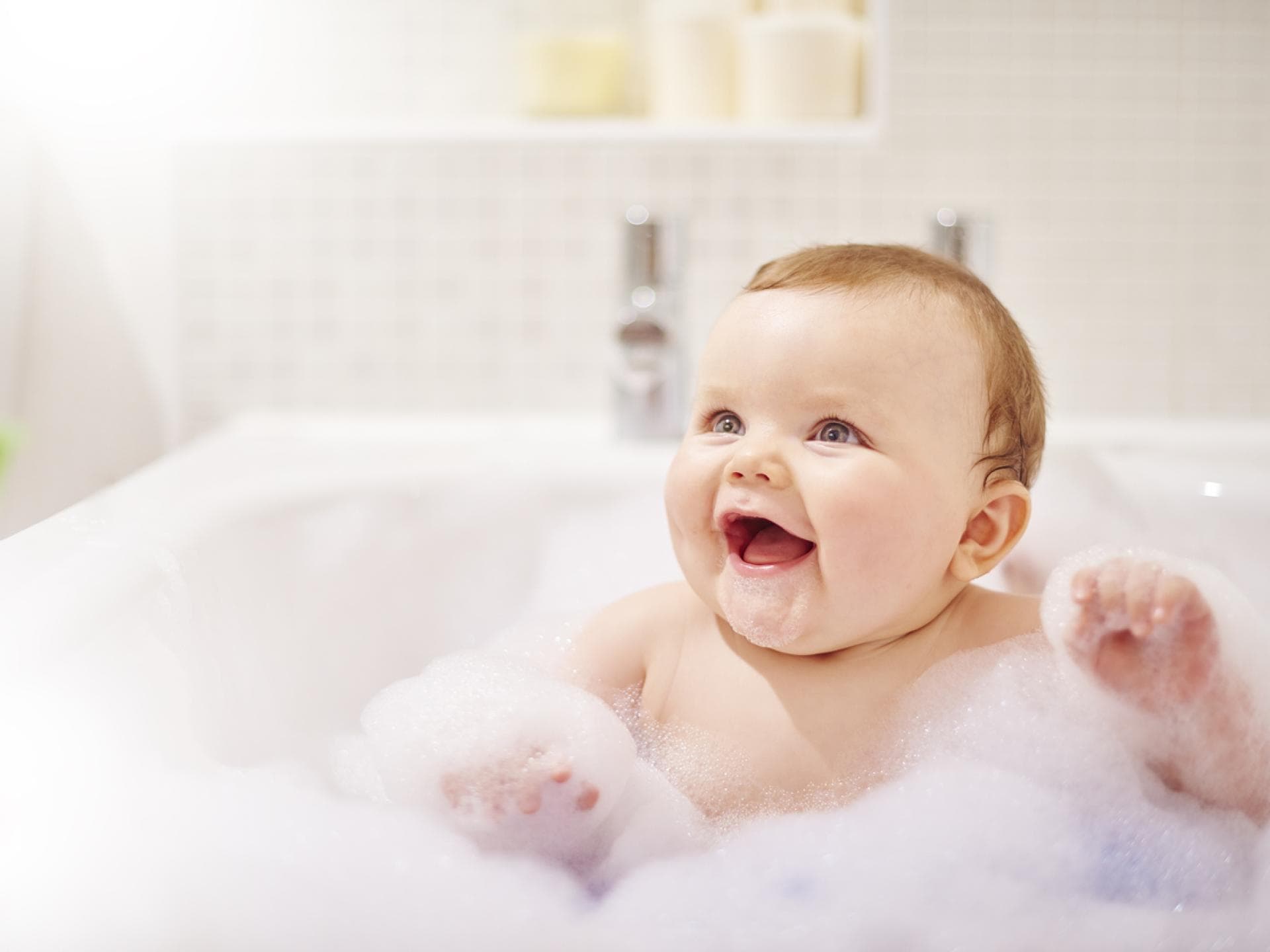 Baby sitzt in der Badewanne mit viel Schaum