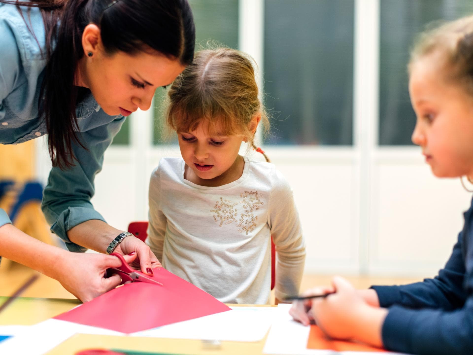 Erzieherin bastelt mit Kindern.