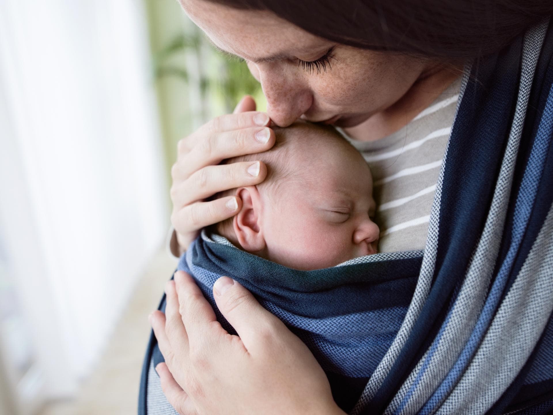 Mama hat Neugeborenes in Babytrage