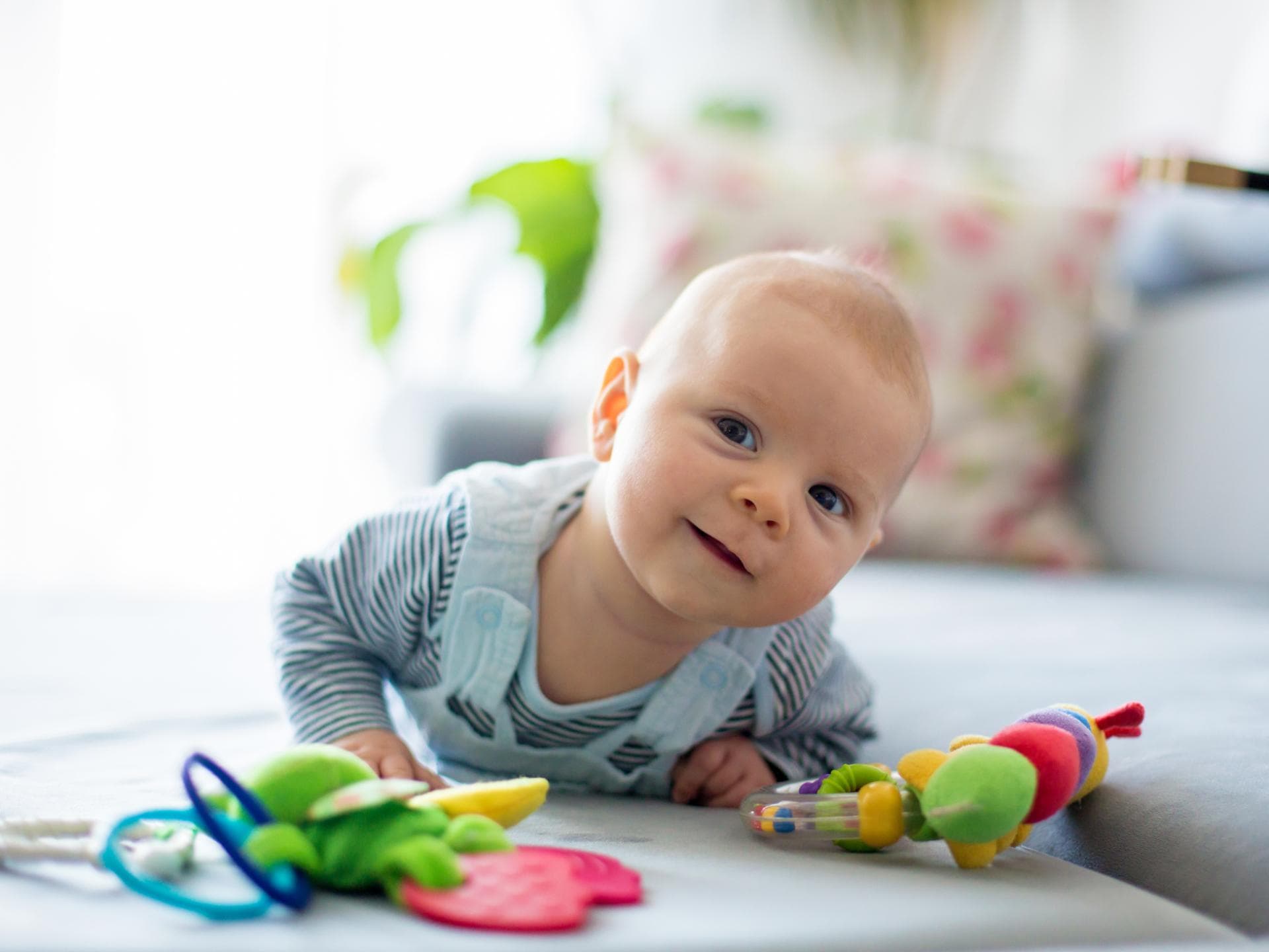 Bei diesen Jungennamen dreht sich alles um den Buchstaben N. Ein Baby liegt auf dem Sofa und spielt.