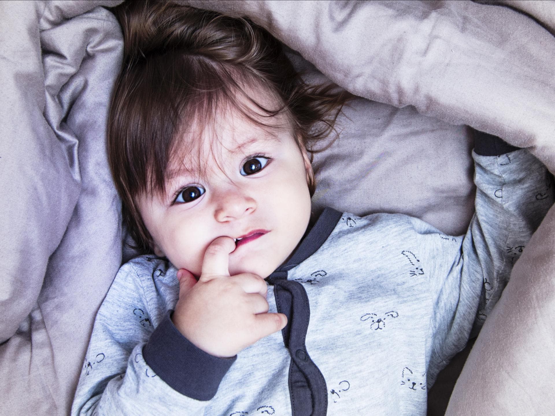 Die 2-3-4-Stunden Regel ist perfekt für Babys Schlaf. Ein kleines Kind liegt im Bett und kann nicht einschlafen.