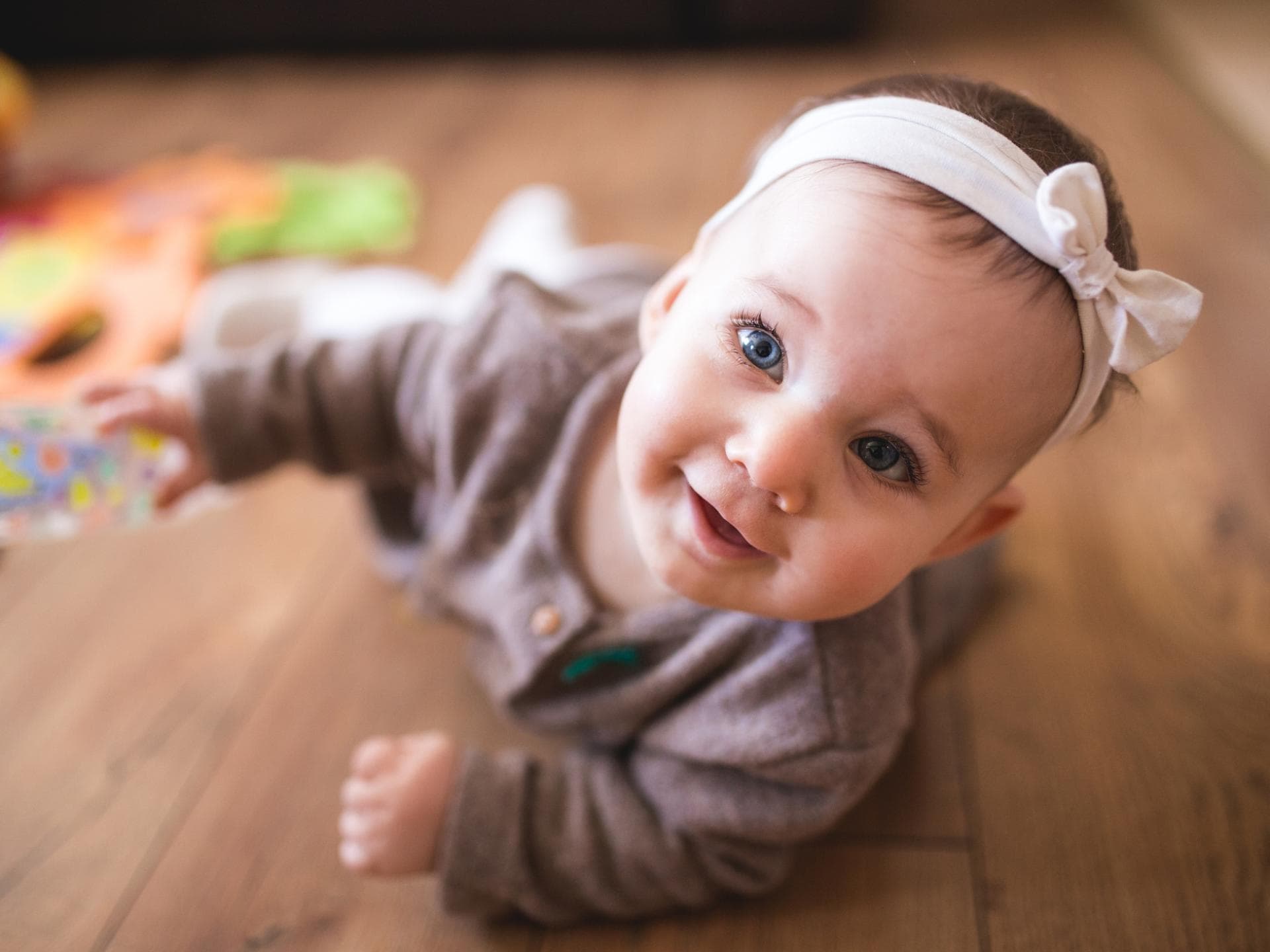 Mädchennamen mit V sind oft außergewöhnlich. Ein Baby krabbelt neben Spielsachen auf dem Boden.