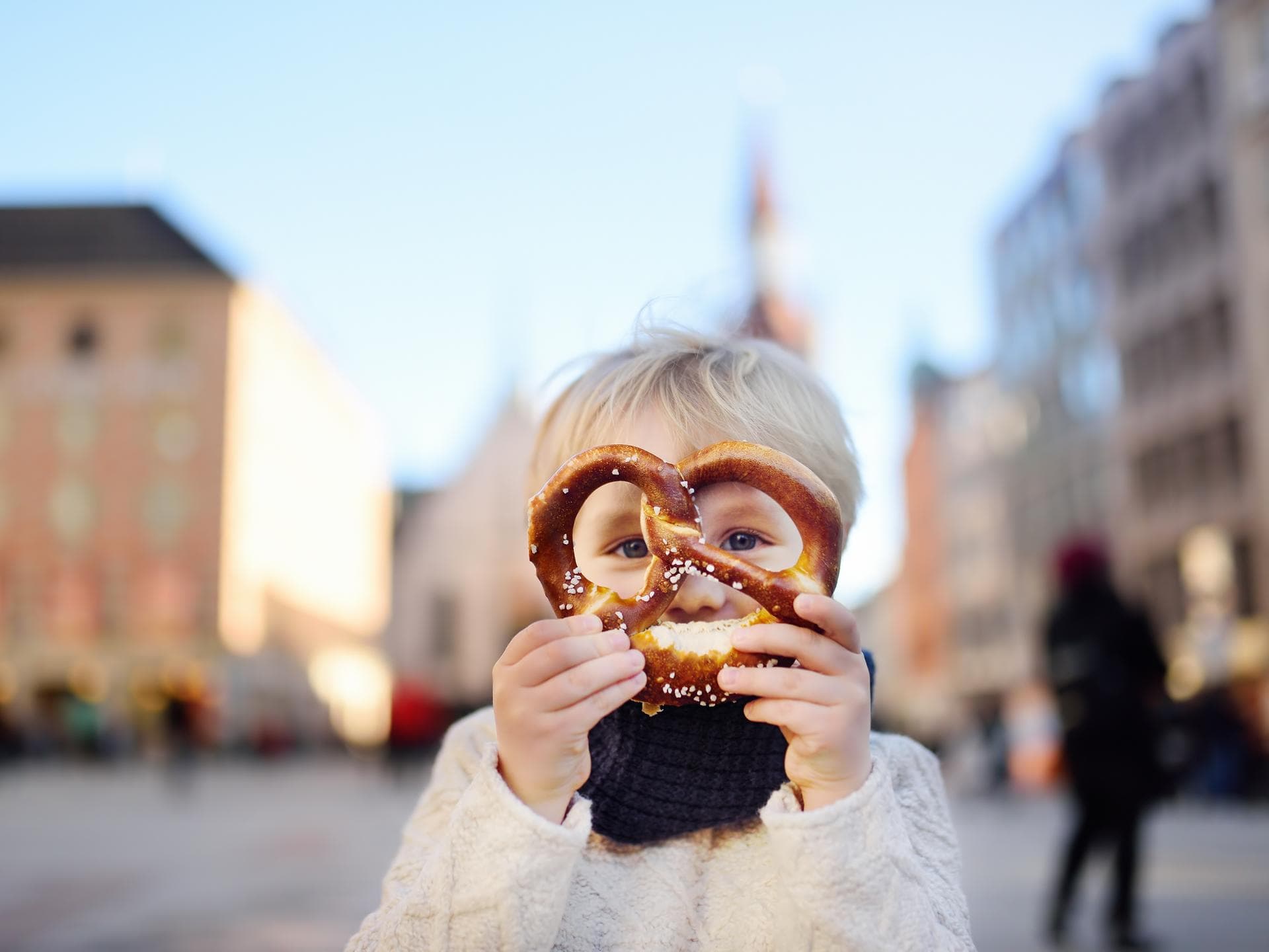 Typische bayerische Jungennamen, wie Ludwig oder Caspar, sind wieder modern. Ein kleiner Junge hält sich eine Brezel vor das Gesicht.