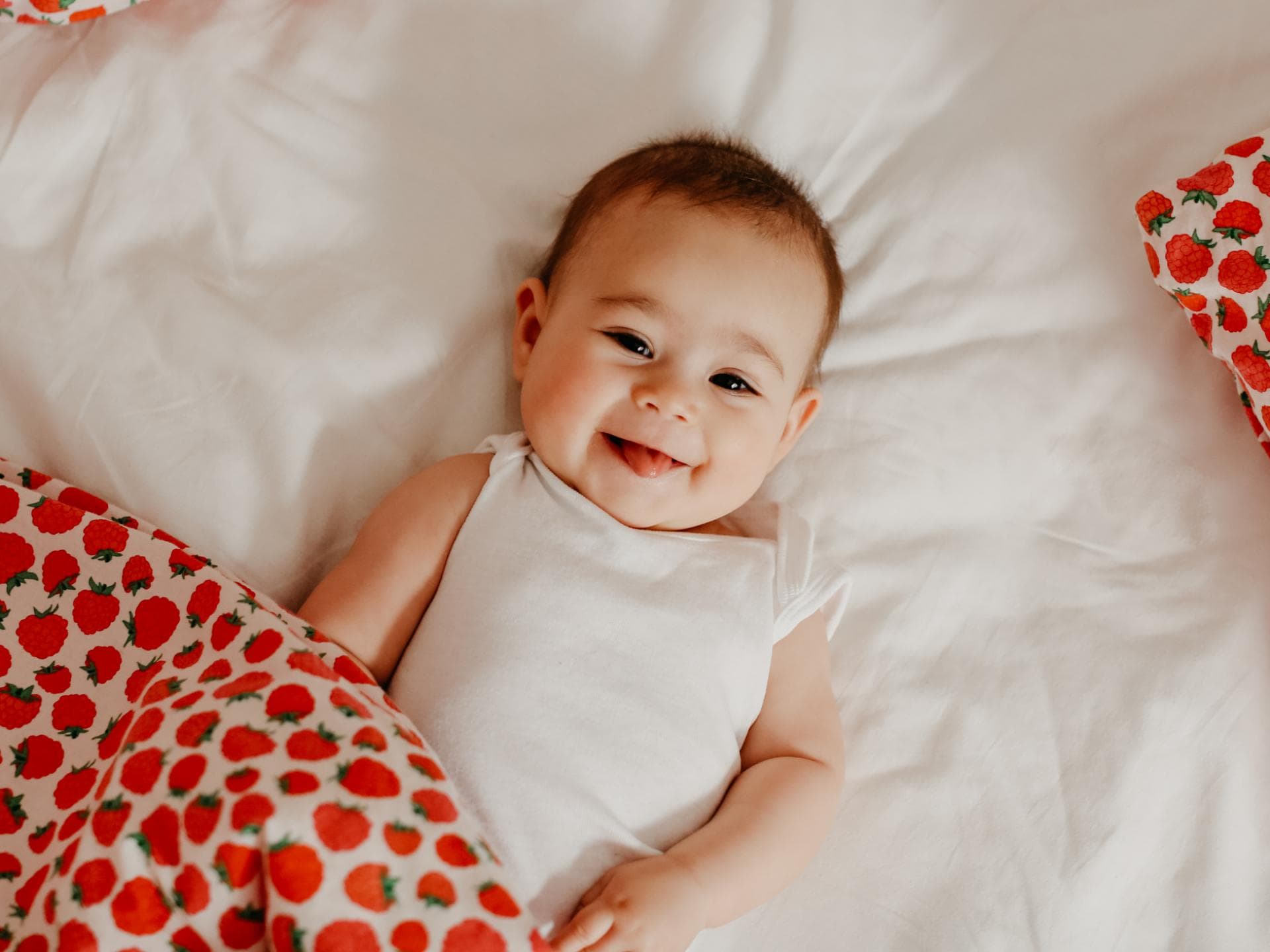 Viele Mädchennamen mit K sind sehr beliebt. Ein Baby liegt lächelnd in seinem Bett