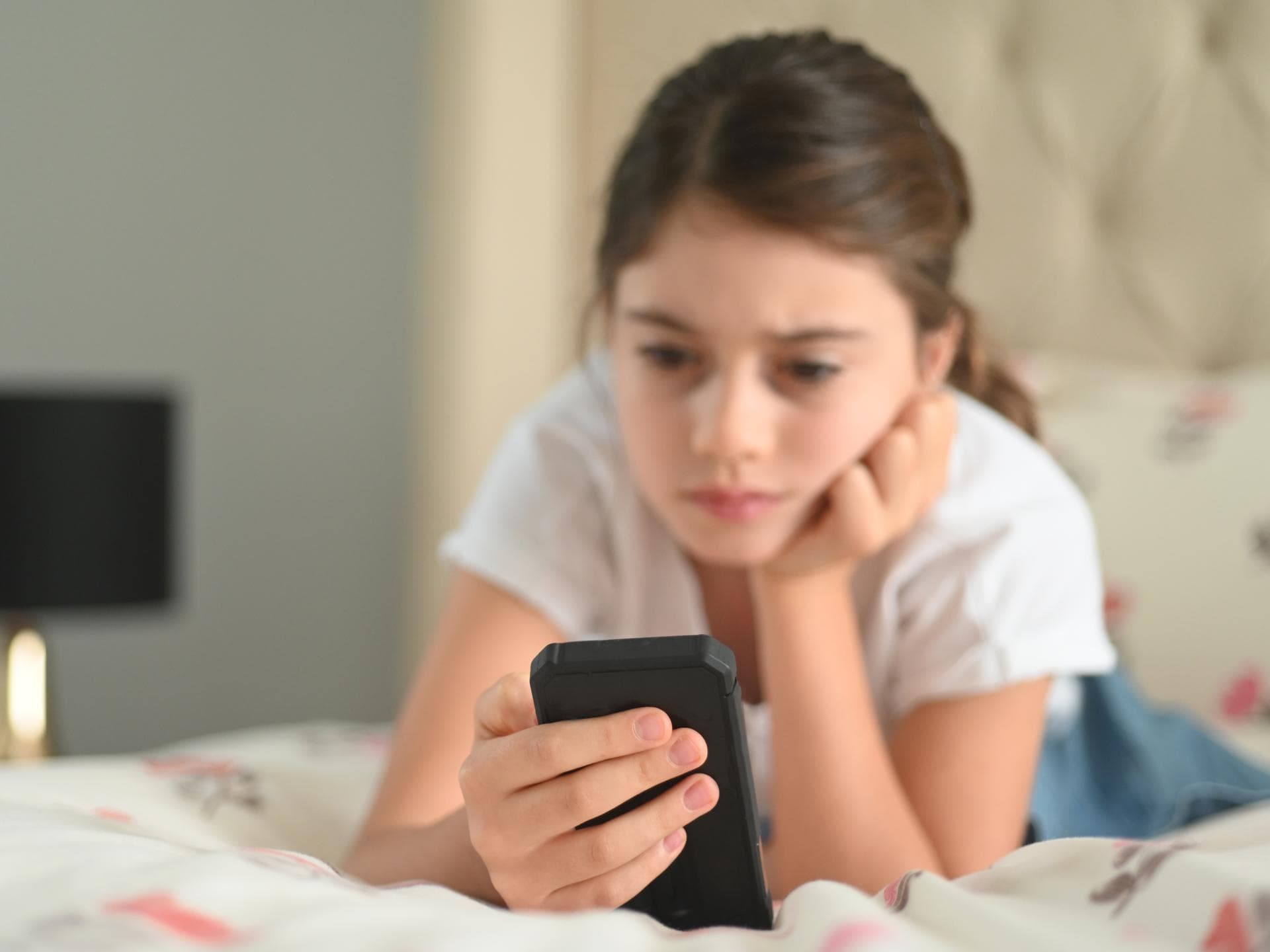 Kinder und Jugendliche verbringen unterschiedlich viel Zeit am Smartphone. Mädchen am Smartphone.