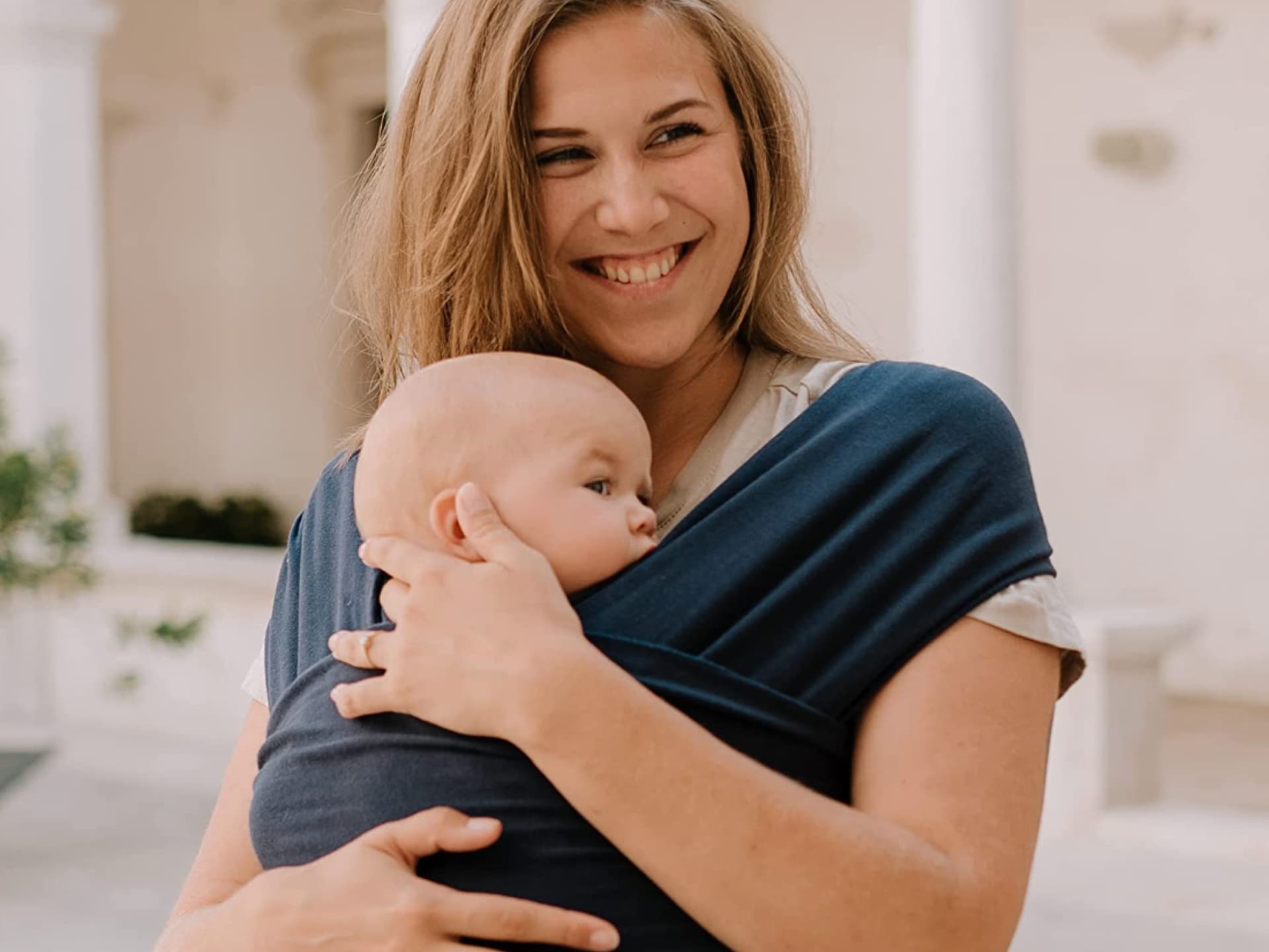 Mama trägt Baby in Tragetuch