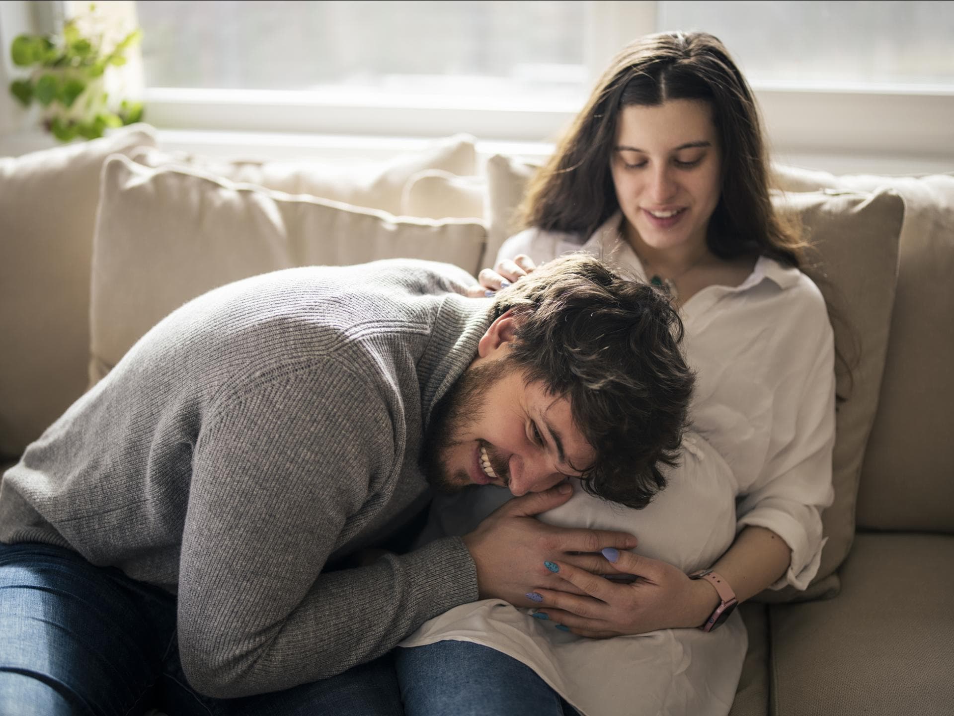 Werdender Papa legt Kopf auf Babybauch seiner Frau