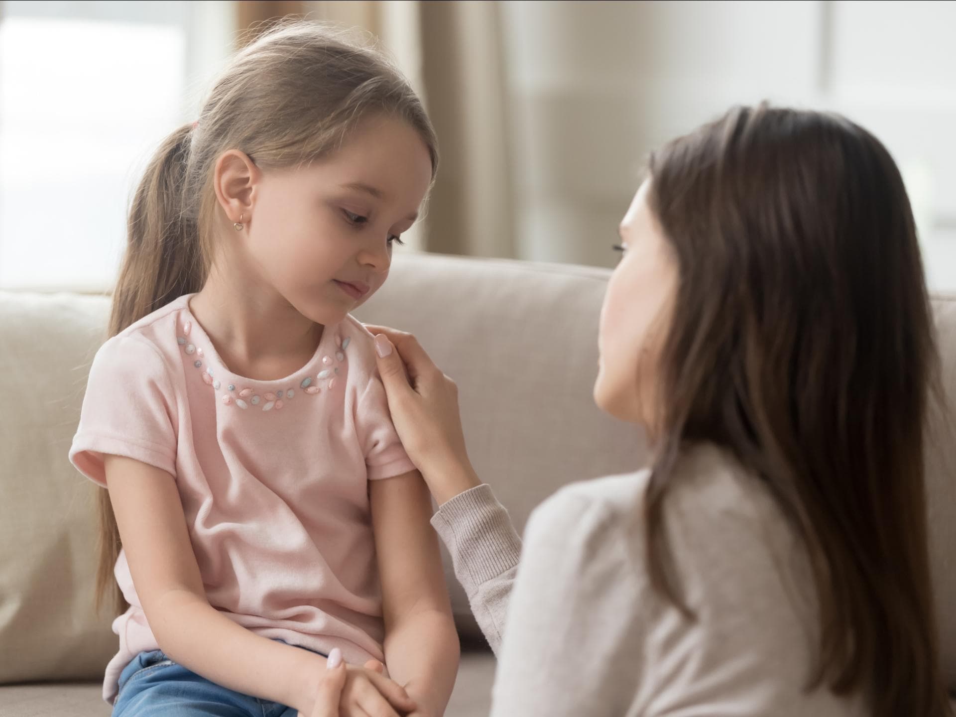 Wenn das Kind nichts von der Kita erzählen mag ... Kind sitzt auf dem Sofa und die Mutter spricht zu ihm