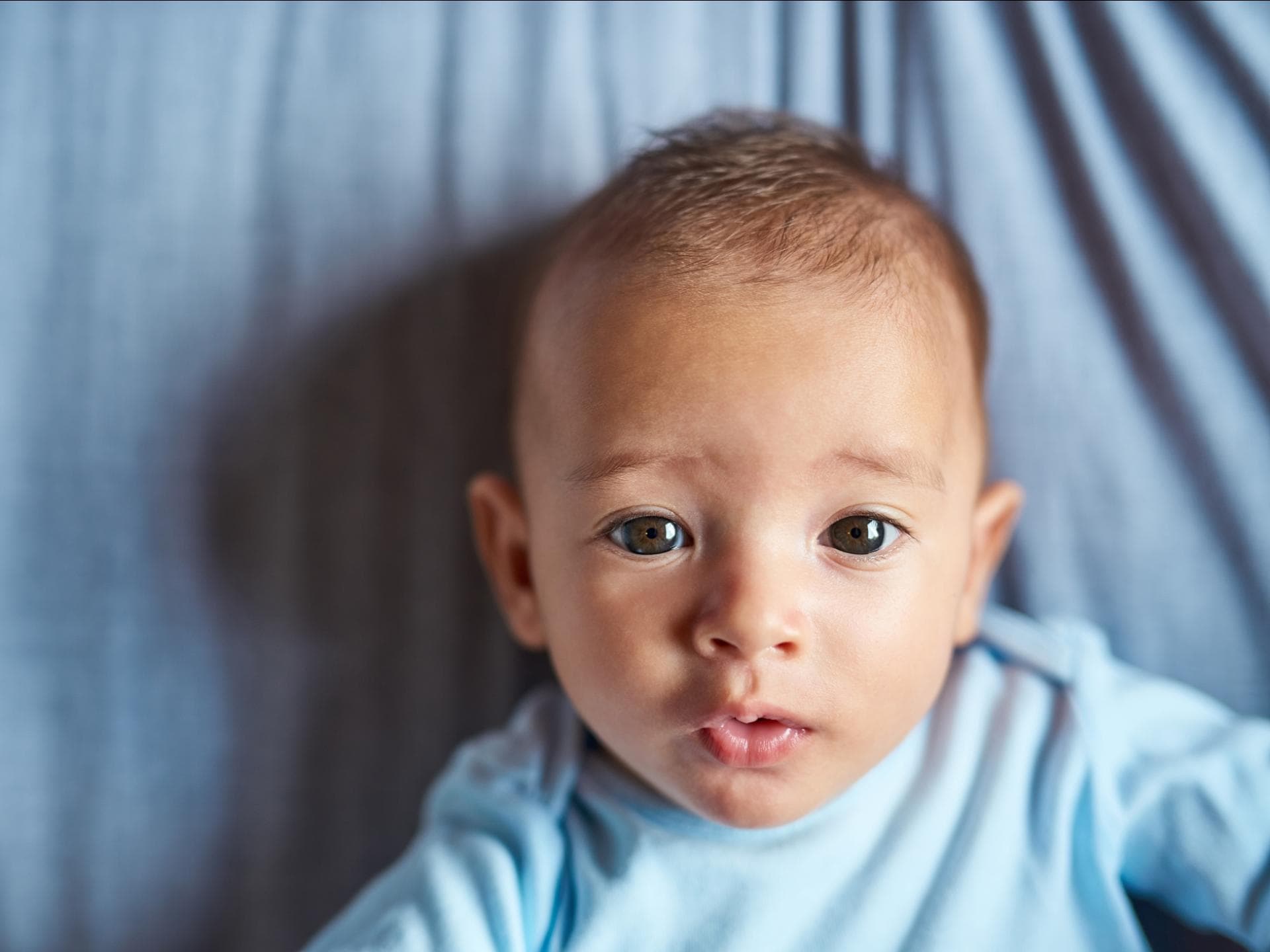 Türkische Jungennamen Ein kleines Baby, das süß in die Kamera guckt.