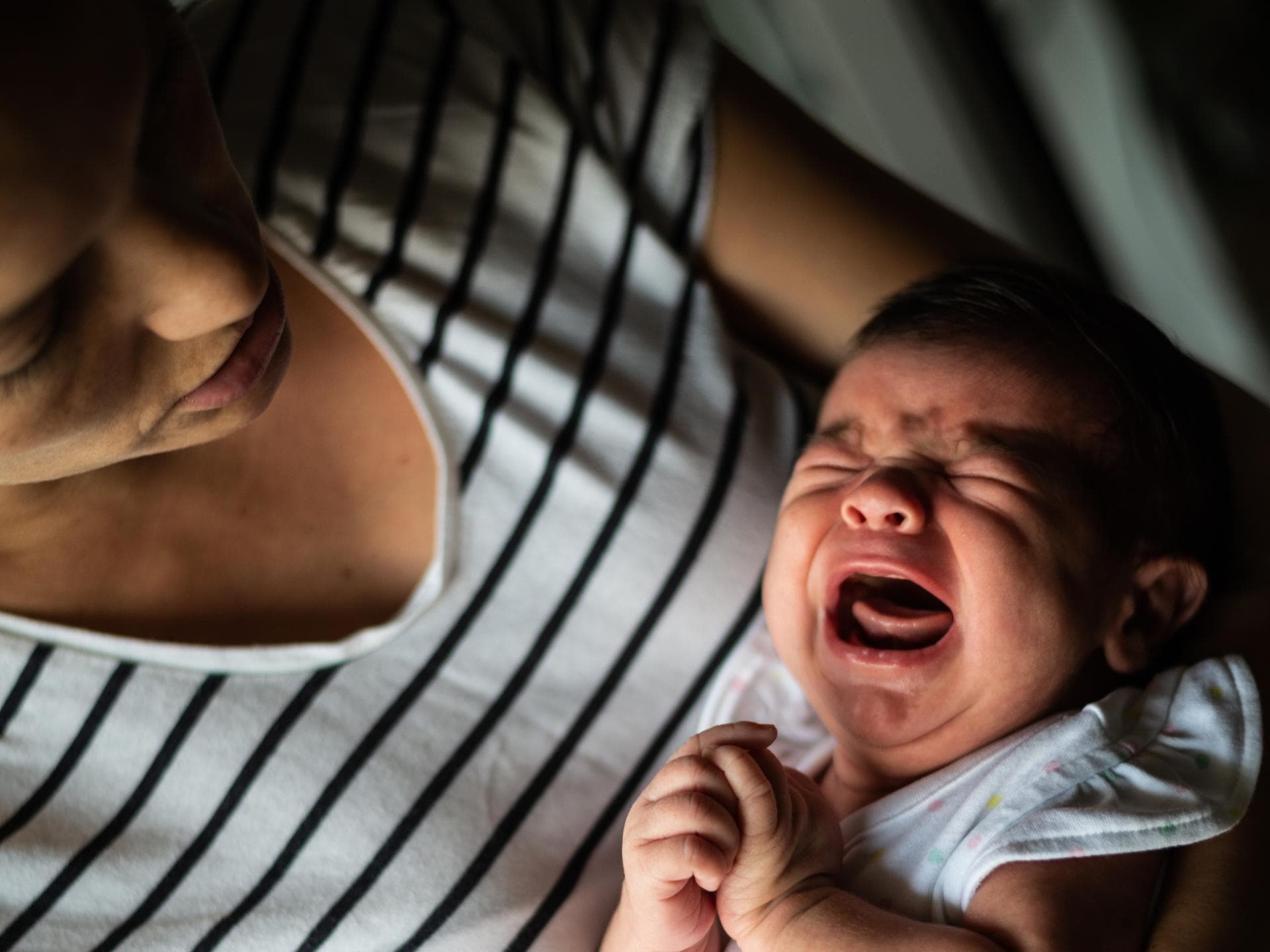 Mutter hält ihr schreiendes Baby im Arm.