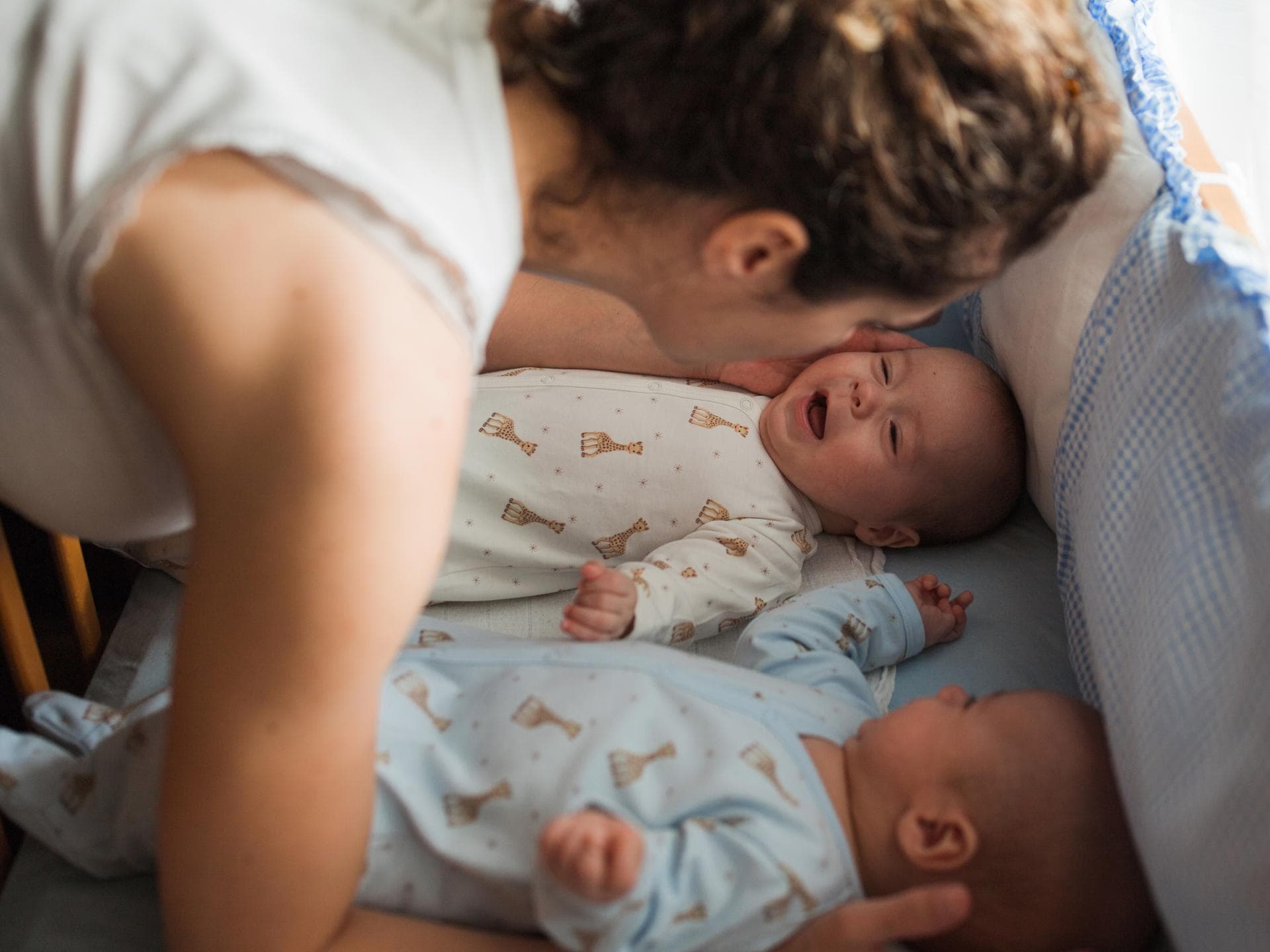 Mama legt zwei Babys ins Bett.