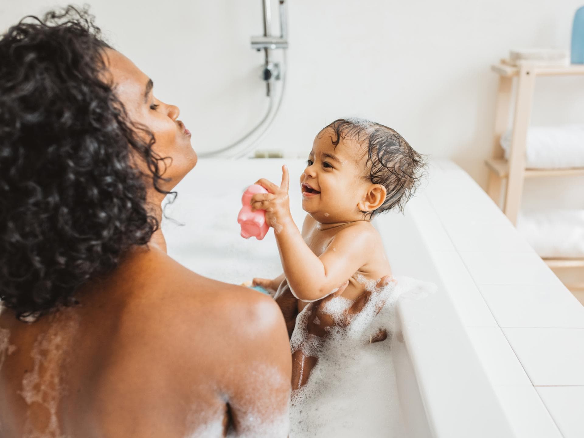 Eine Mutter badet mit ihrem Baby zusammen in der Badewanne. 