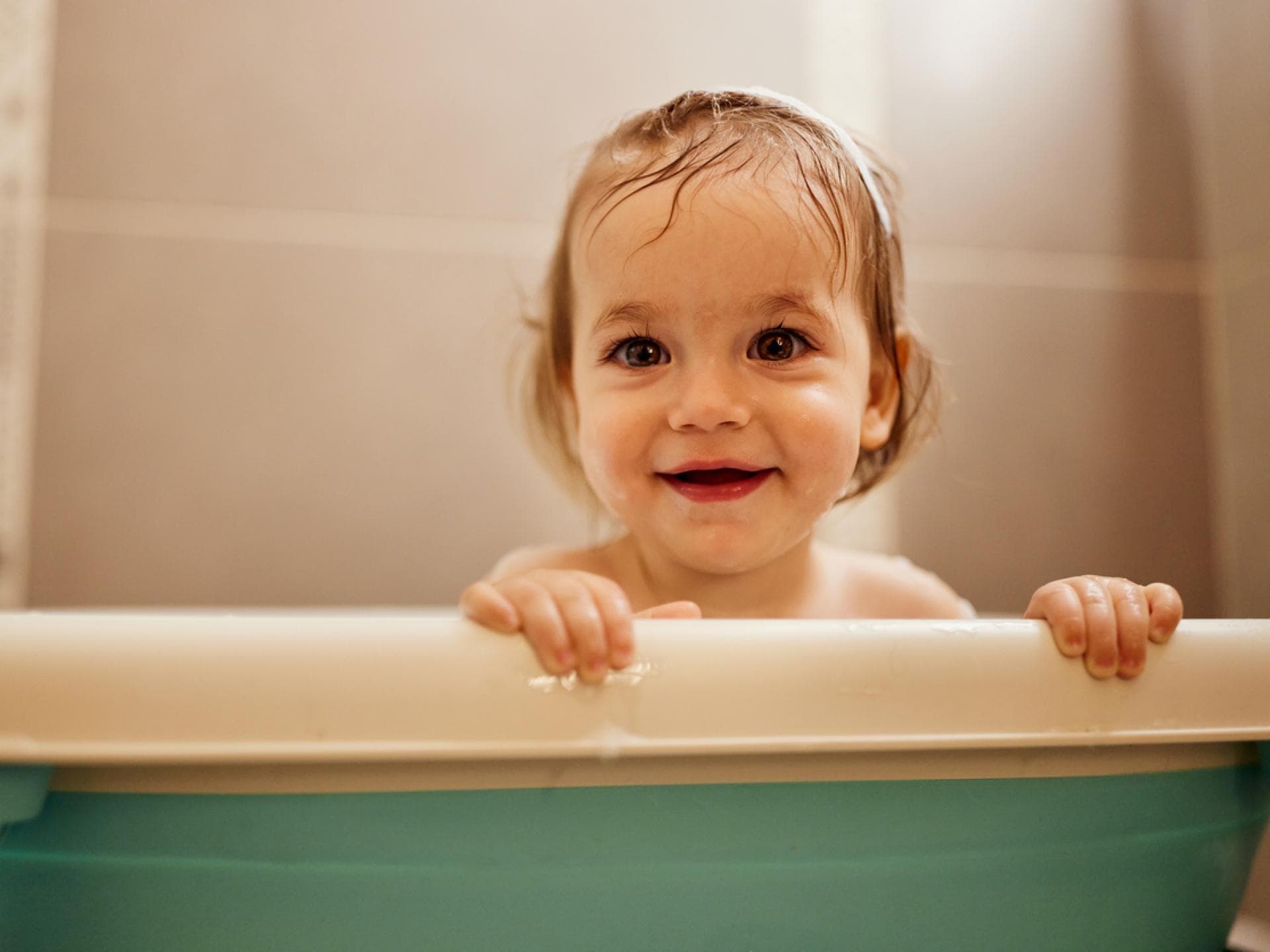 Baby-Mädchen schaut niedlich aus der Babywanne – aber wie lange? Baby-Mädchen schaut niedlich aus der Babywanne – aber wie lange?