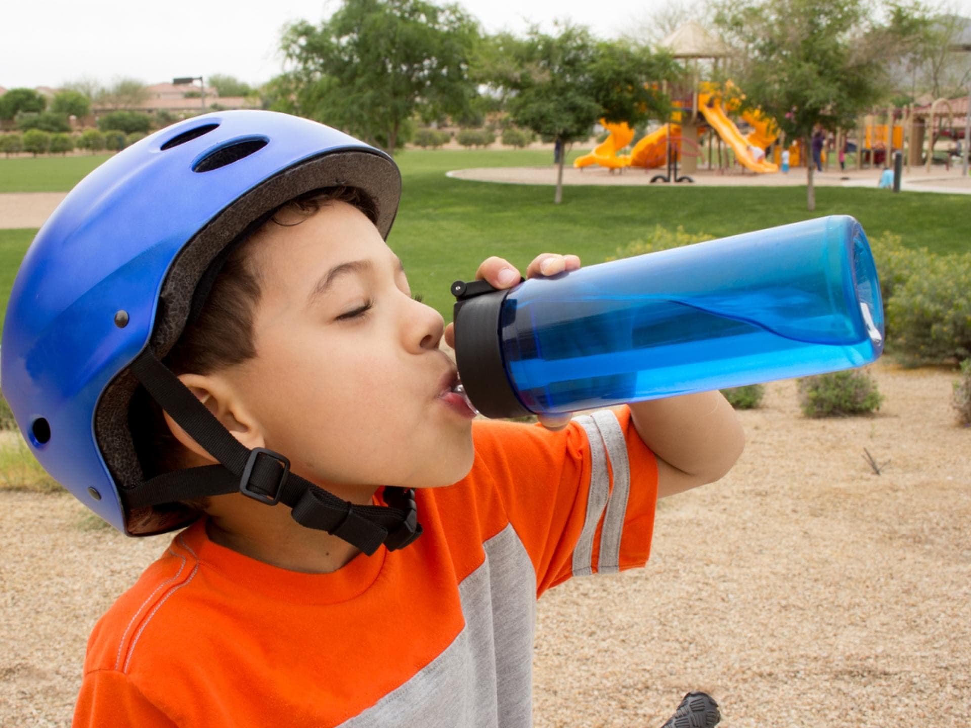 Junge trinkt im Freien aus seiner blauen Trinkflasche – doch wie reinigt man die am besten?