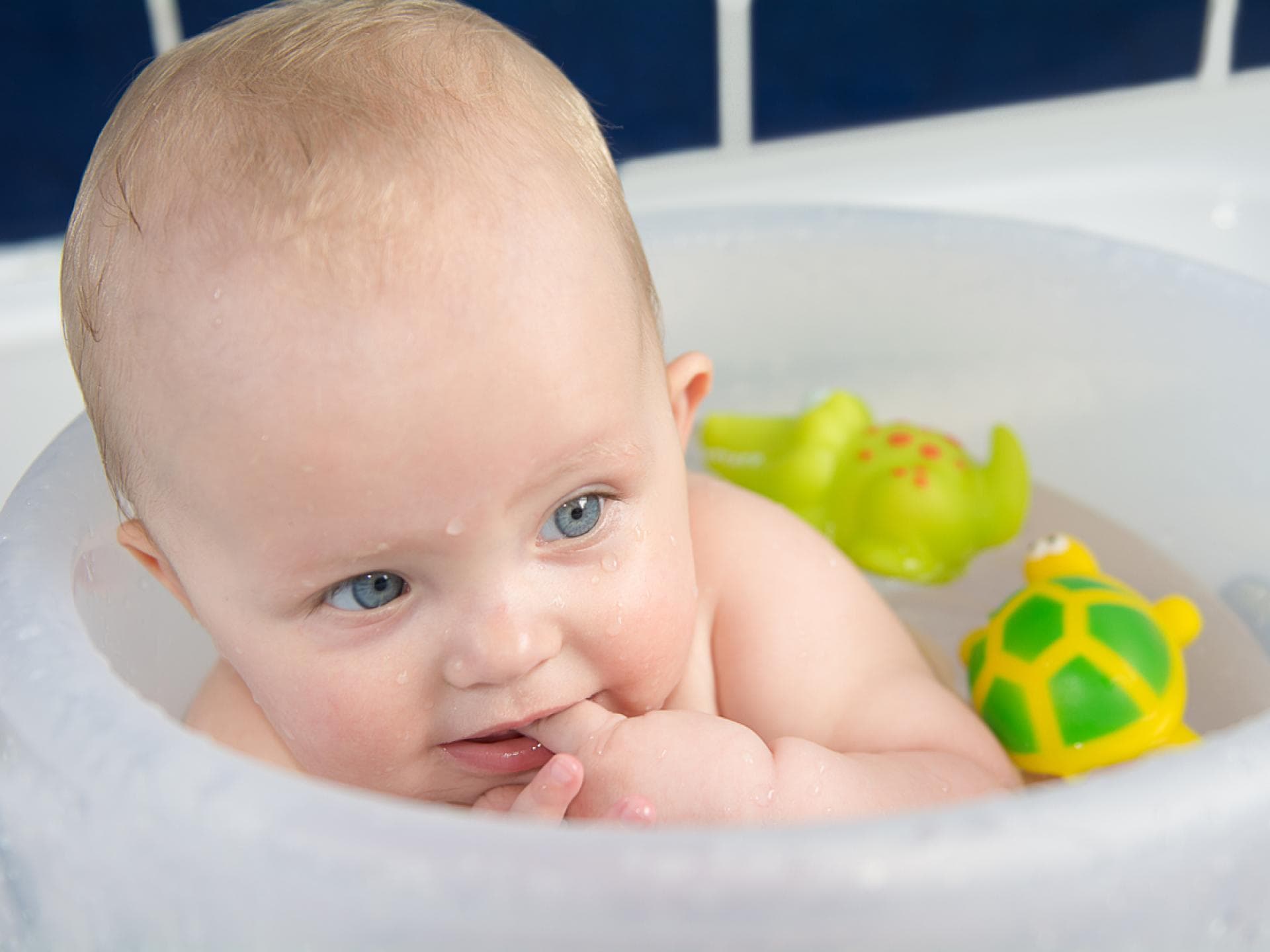 Kleiner Baby-Junge badet im Badeeimer nach Anleitung.