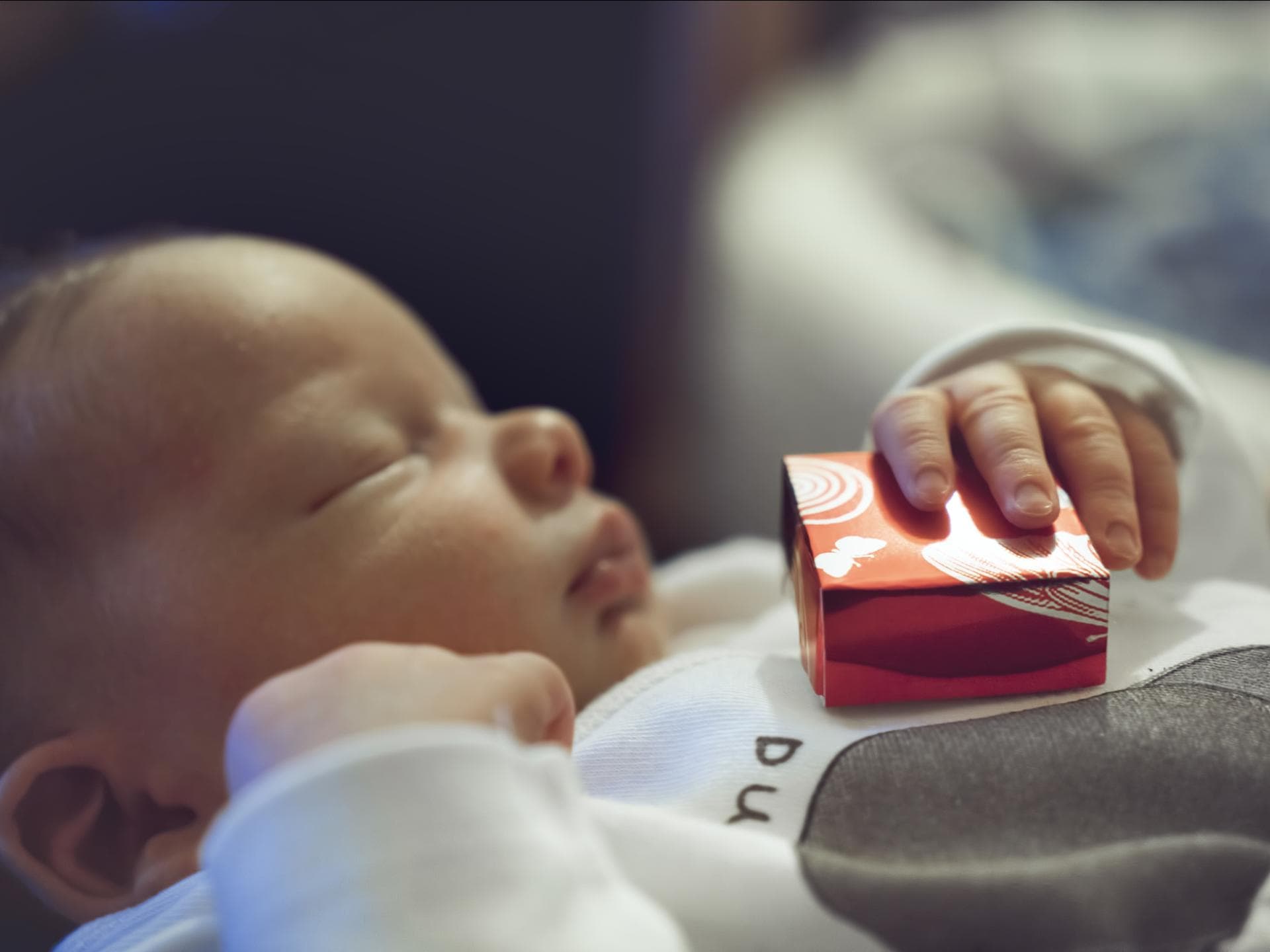 Baby hält Geschenk zur Geburt in der Hand Baby hält Geschenk zur Geburt in der Hand